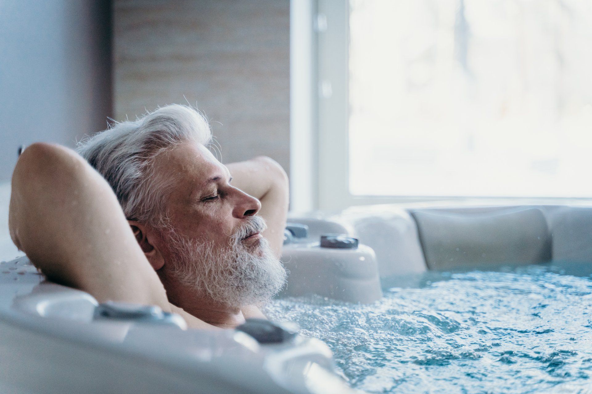 Un homme âgé est allongé dans un bain à remous, les yeux fermés.