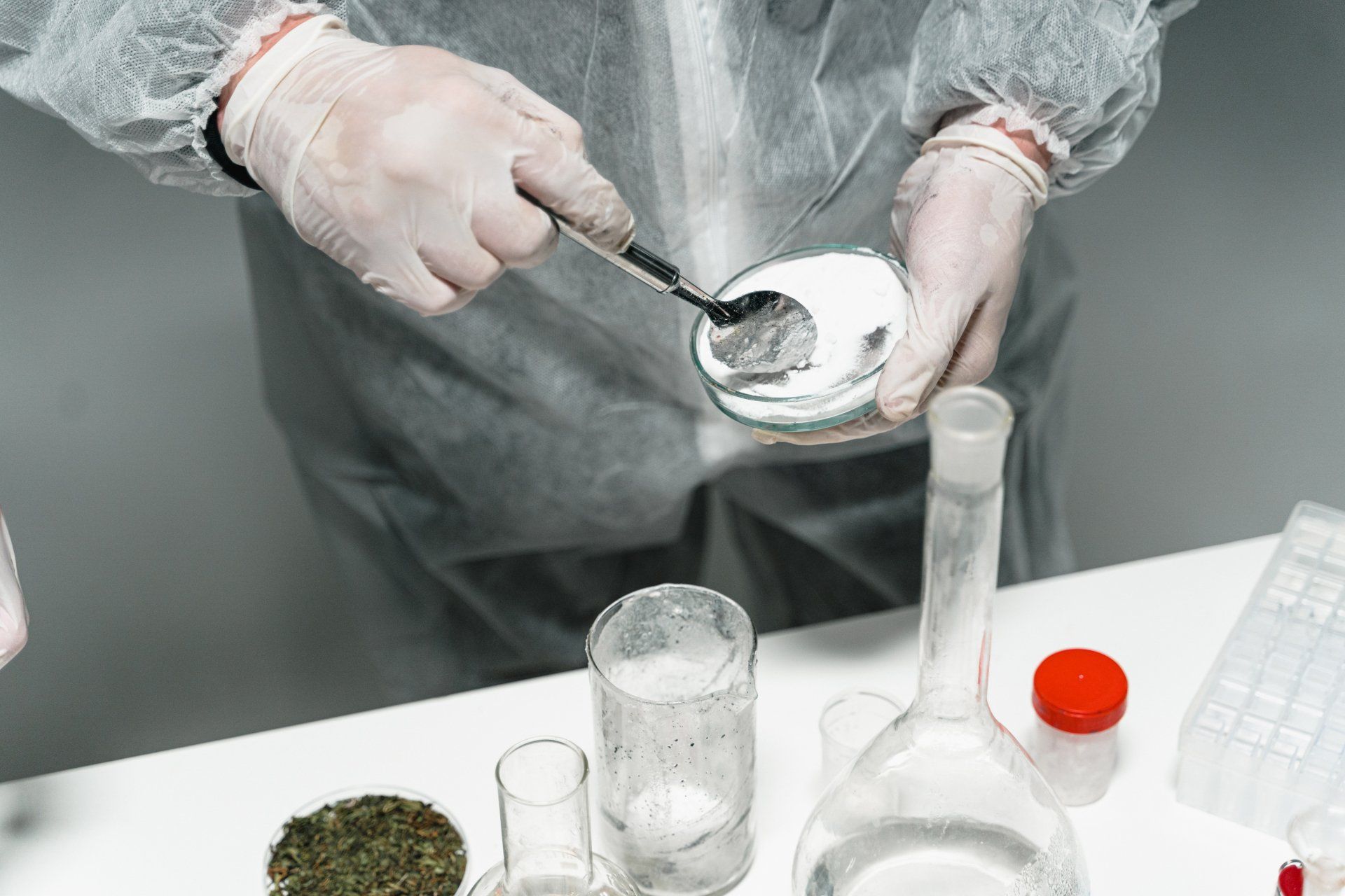 A person is holding a spoon in a petri dish.