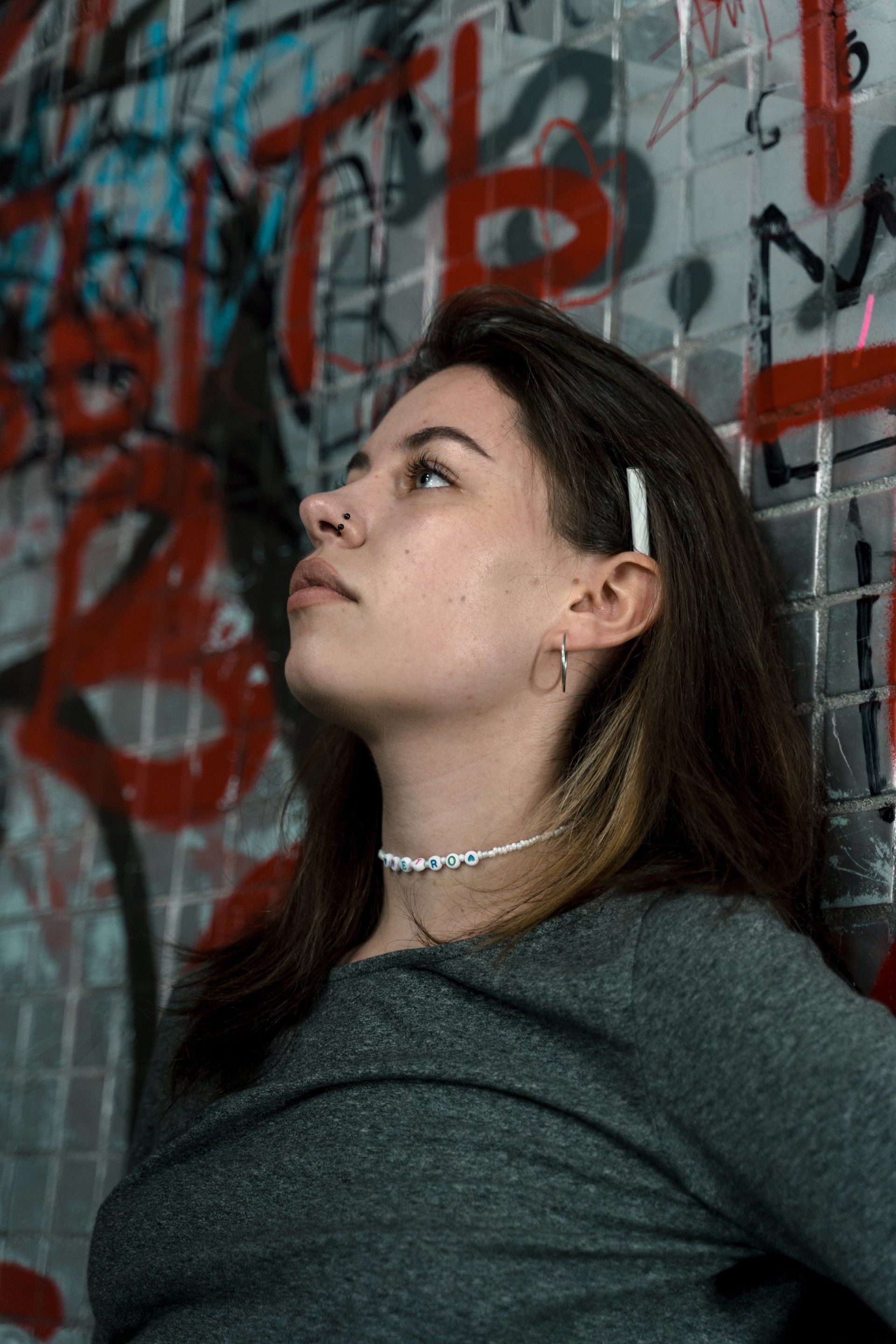 A woman is standing in front of a wall with graffiti on it.