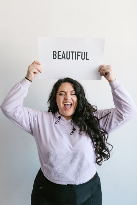 A woman is holding a sign that says beautiful over her head.