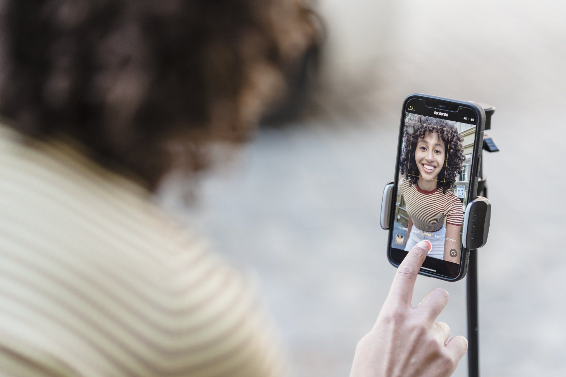 A person is taking a picture of a woman on a cell phone.