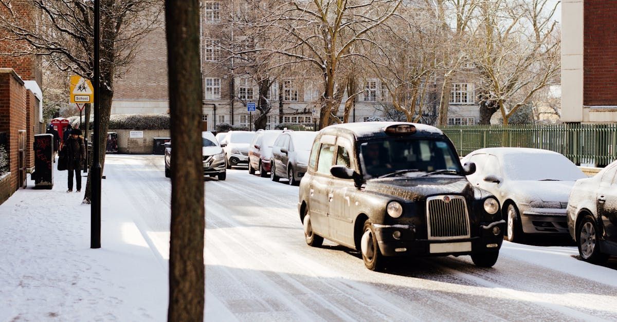 A black taxi cab is driving down a snowy street.