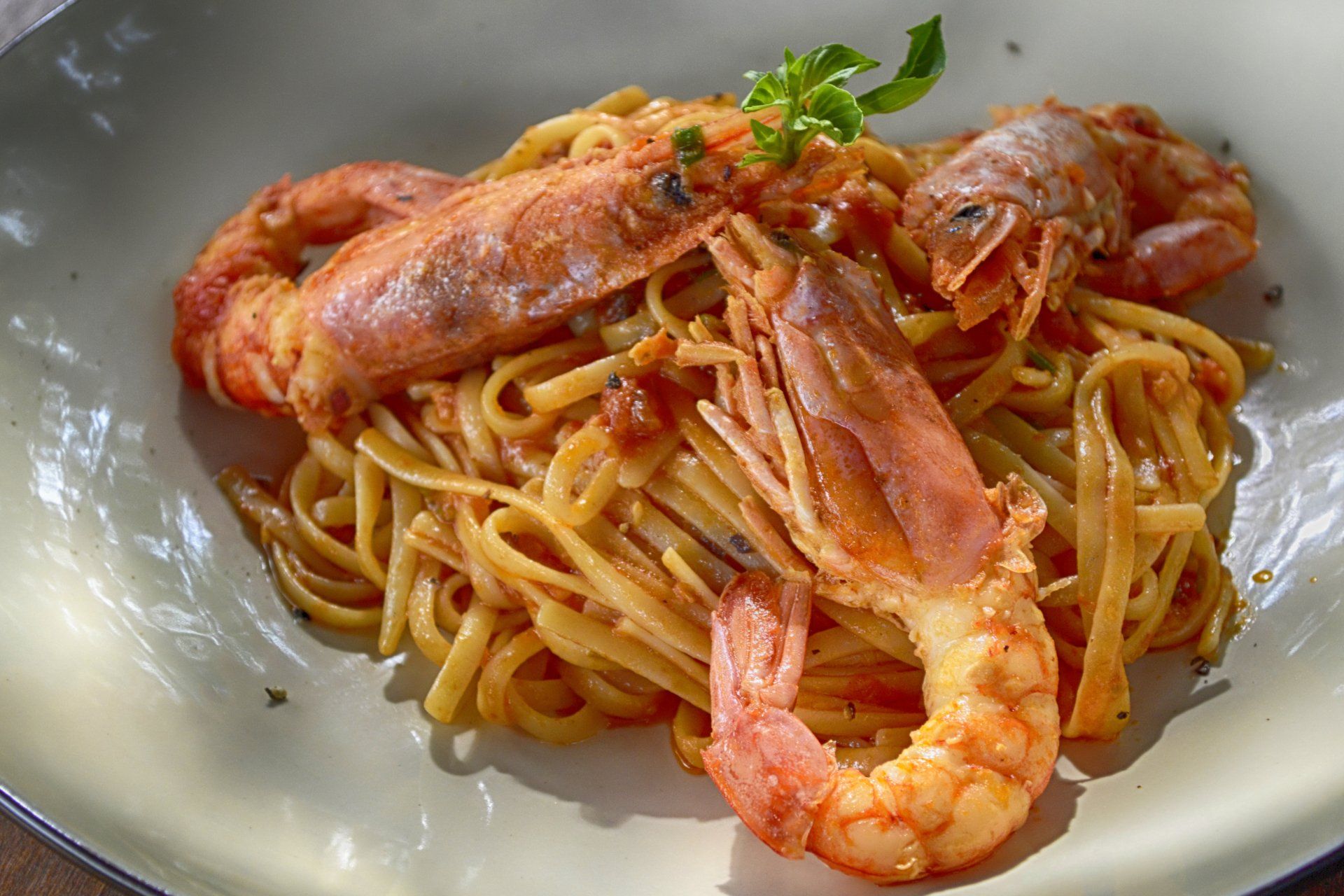 Linguine con gamberi grandi cotti in salsa di pomodoro, servite su un piatto.