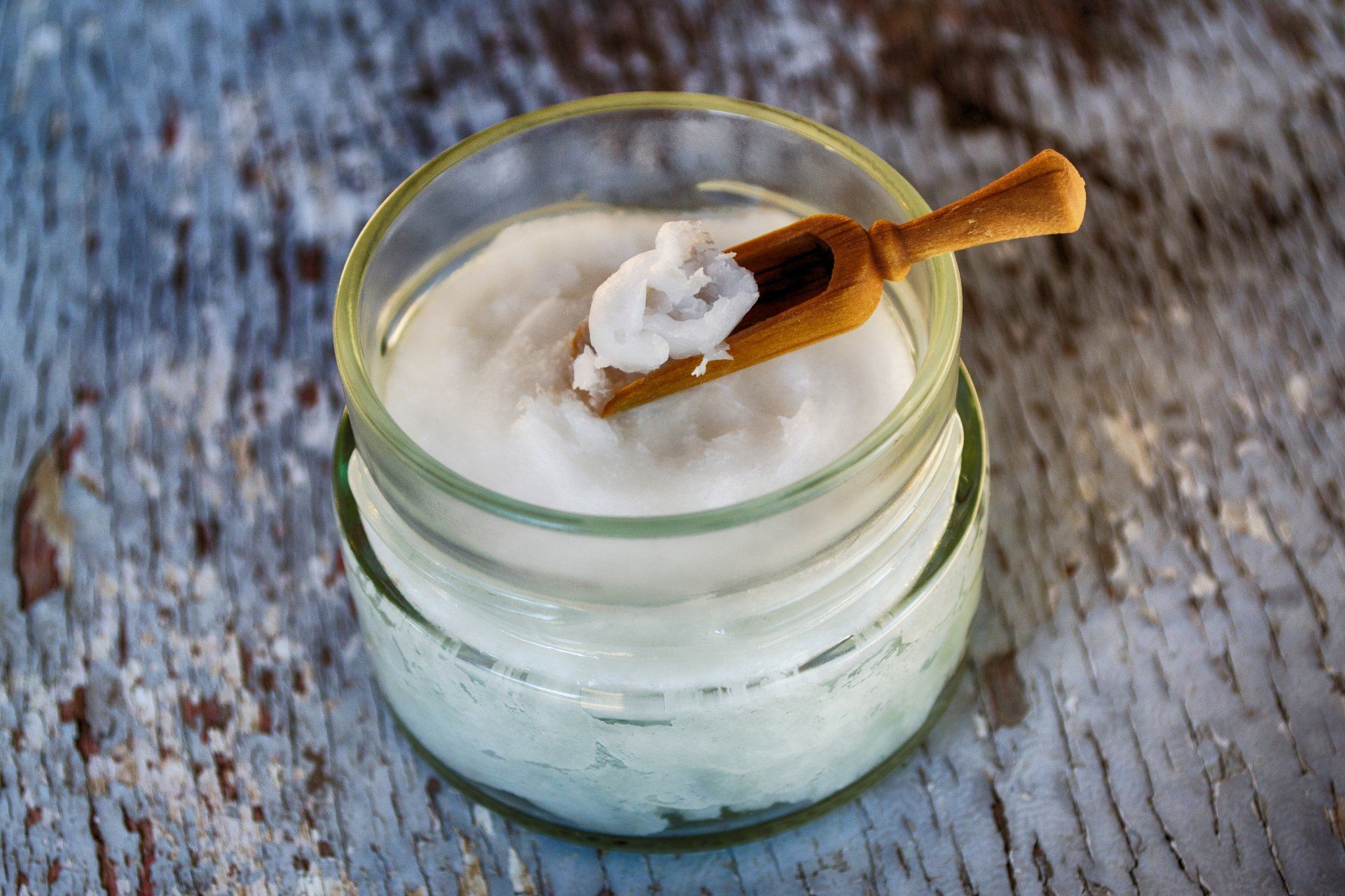 A jar of coconut oil with a wooden spoon in it.