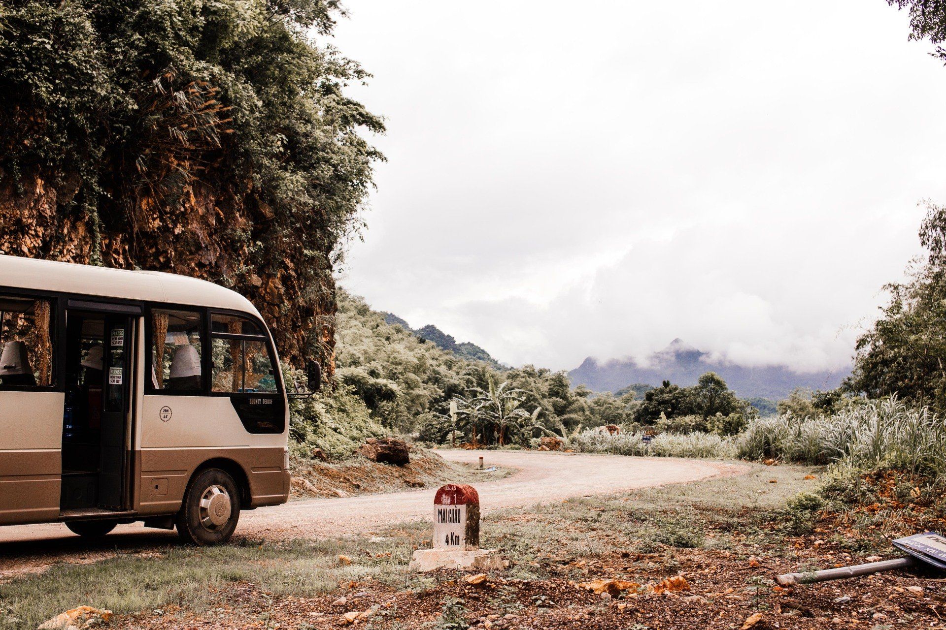 A bus is parked on the side of a dirt road.