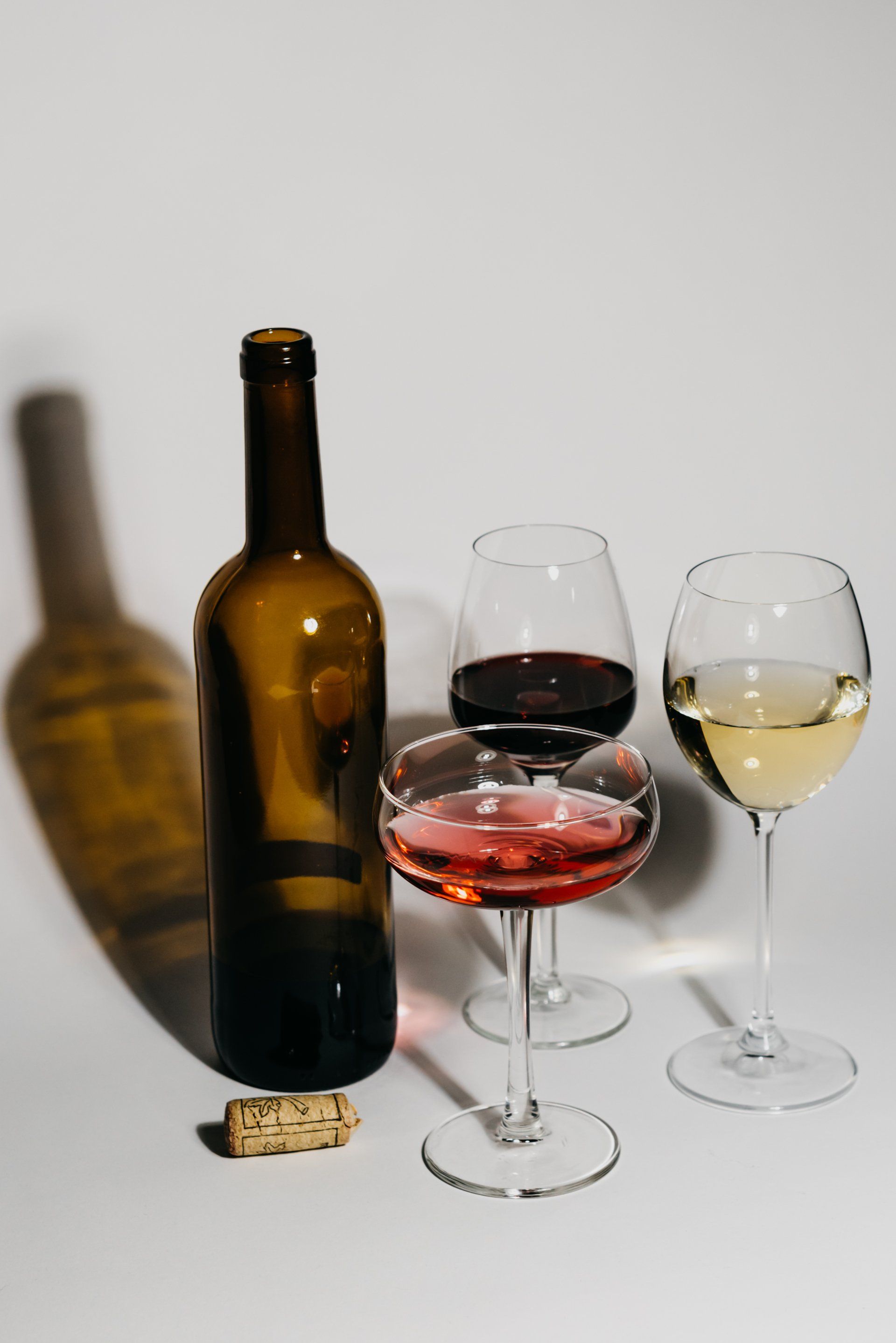 A bottle of wine and three glasses of wine are on a table.