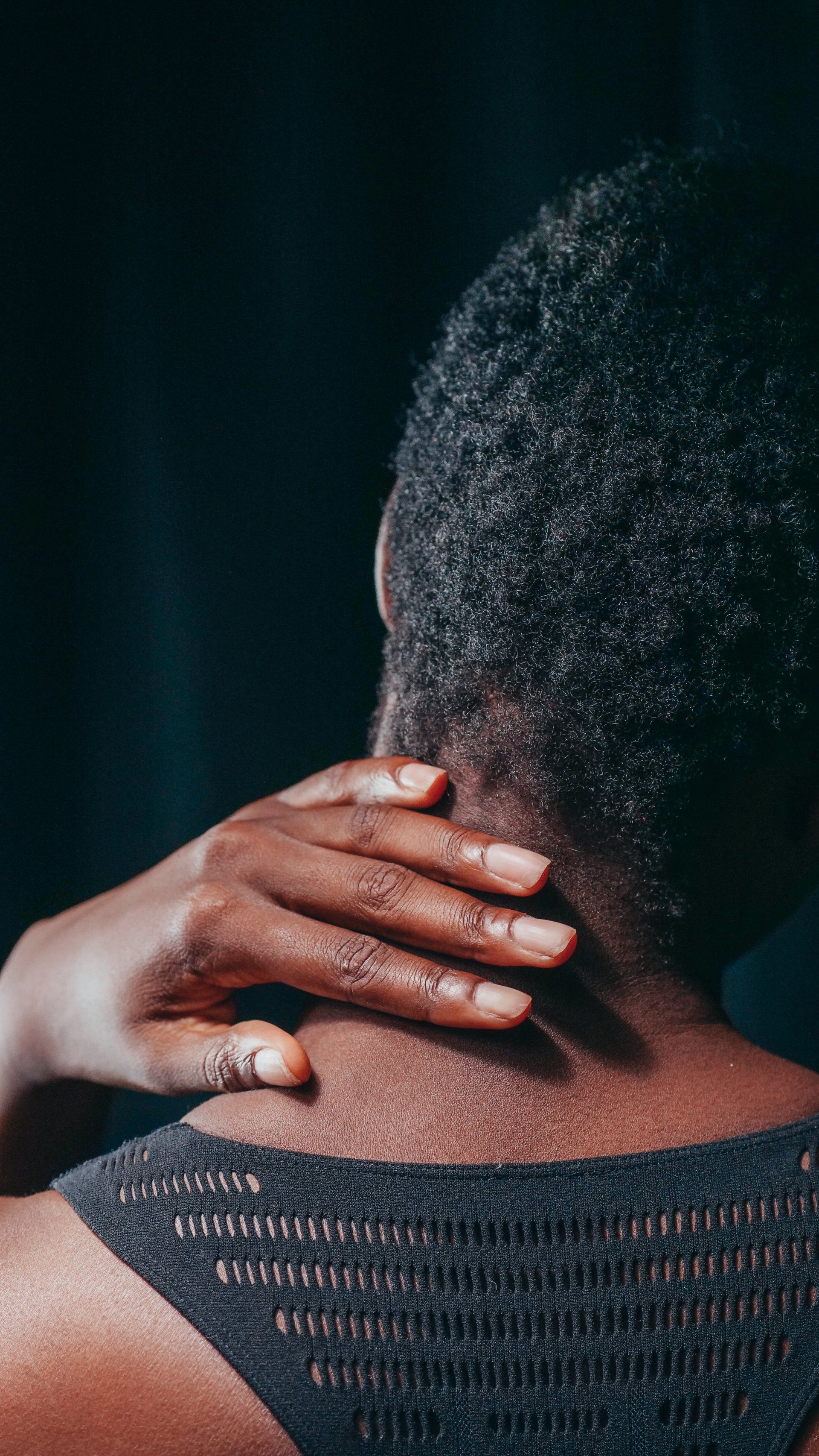 A woman is holding her neck with her hand.