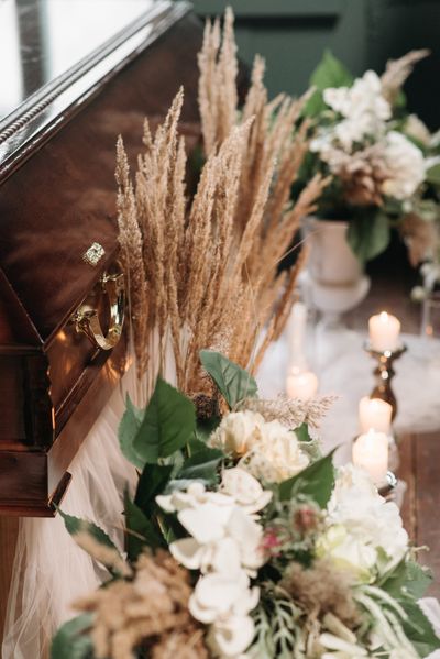 A funeral casket with flowers and candles on it.