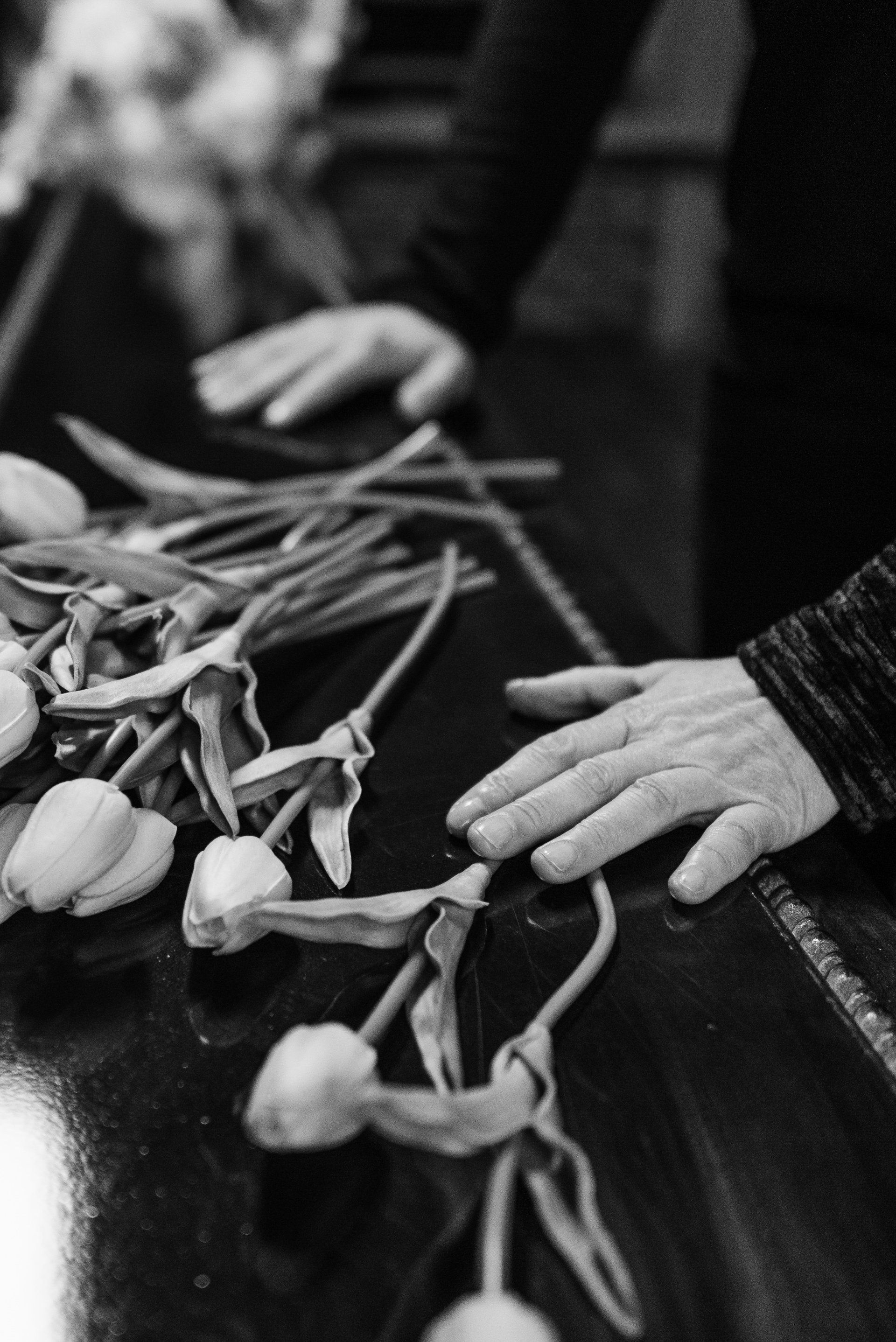 a black and white photo of a person holding a bunch of flowers on a table .