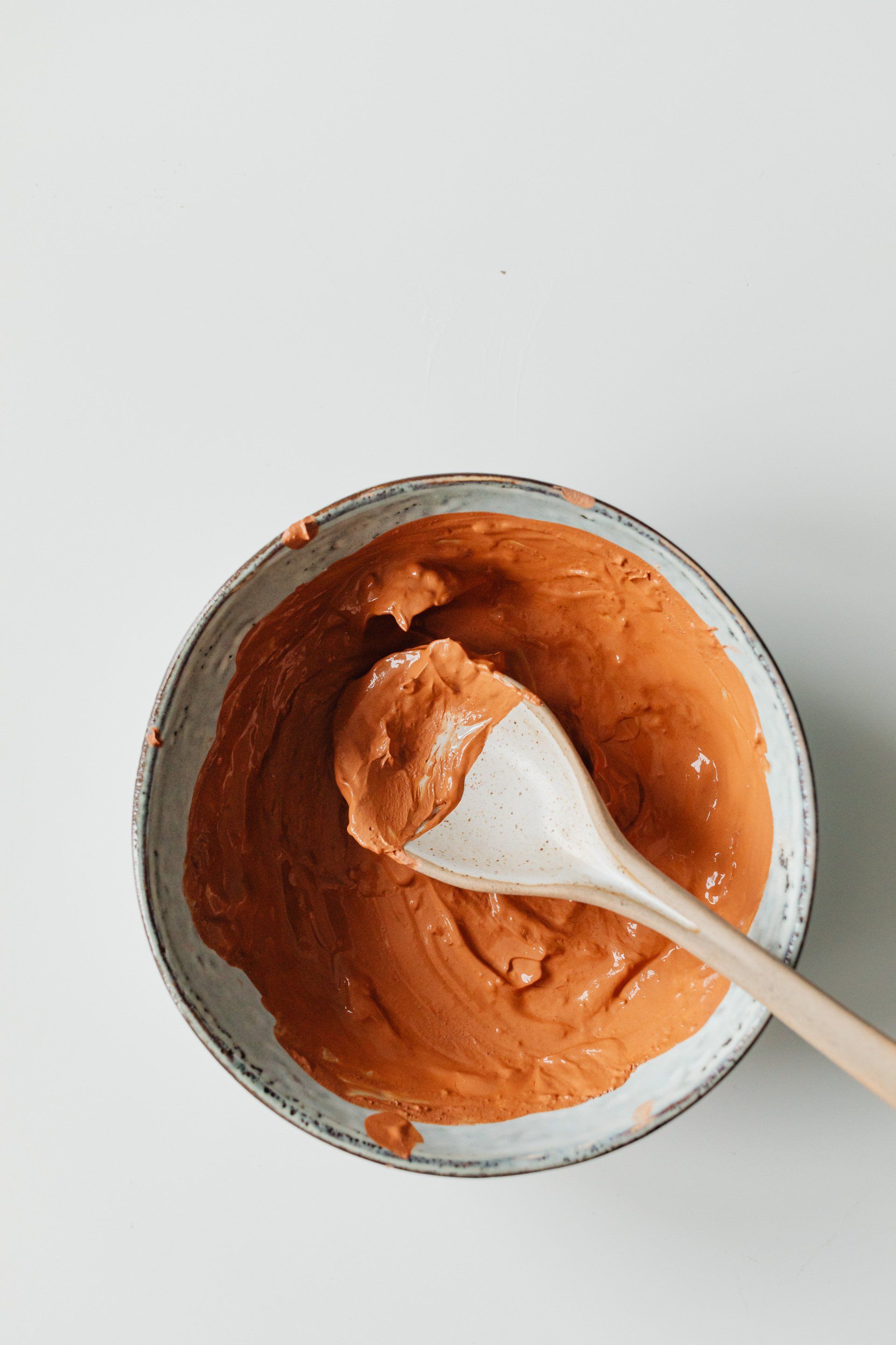 A bowl of brown sauce with a wooden spoon in it.