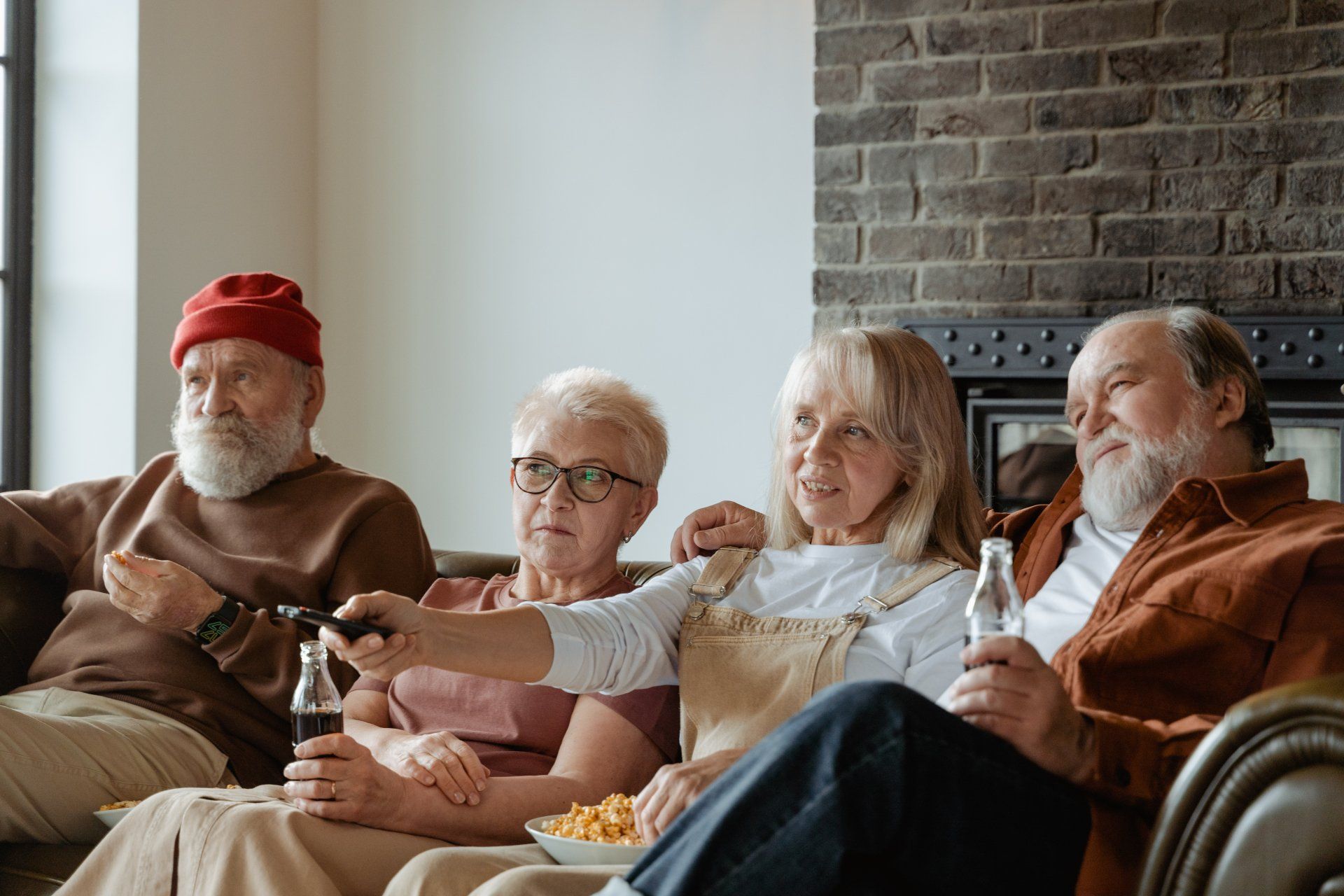 a group of elderly people are sitting on a couch watching tv .