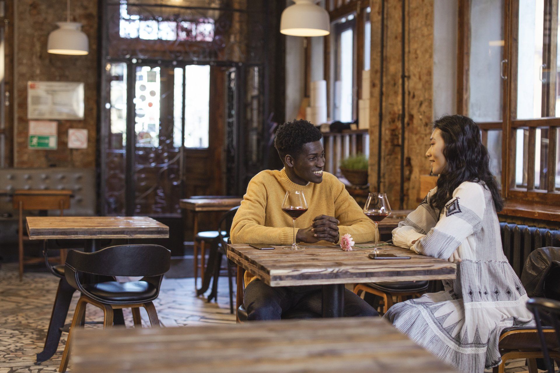 A man and a woman are sitting at a table in a restaurant drinking wine.