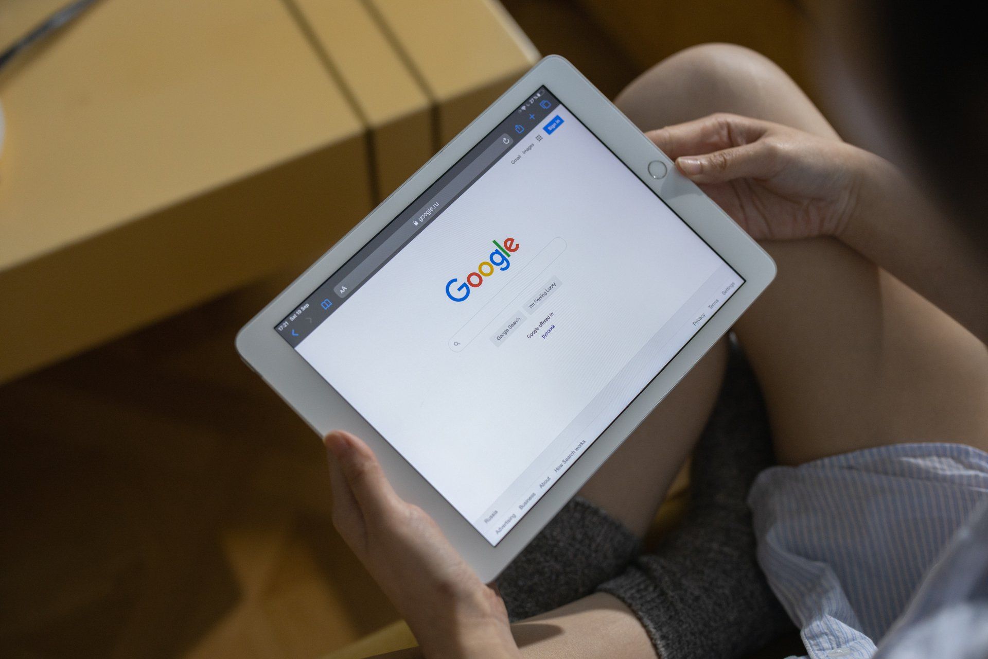 Person holding a white tablet showing the Google homepage