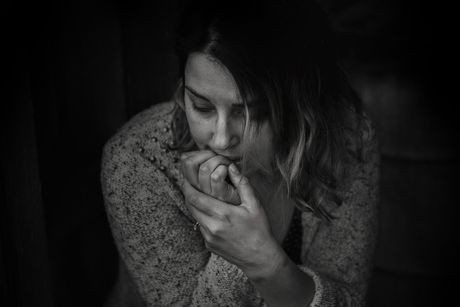 A black and white photo of a woman biting her nails.