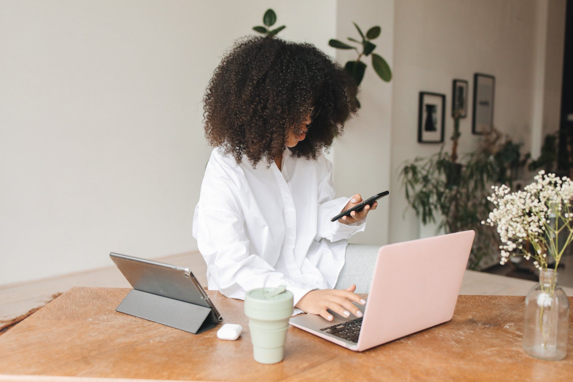 Person multitasking using her phone, computer and tablet at the same time