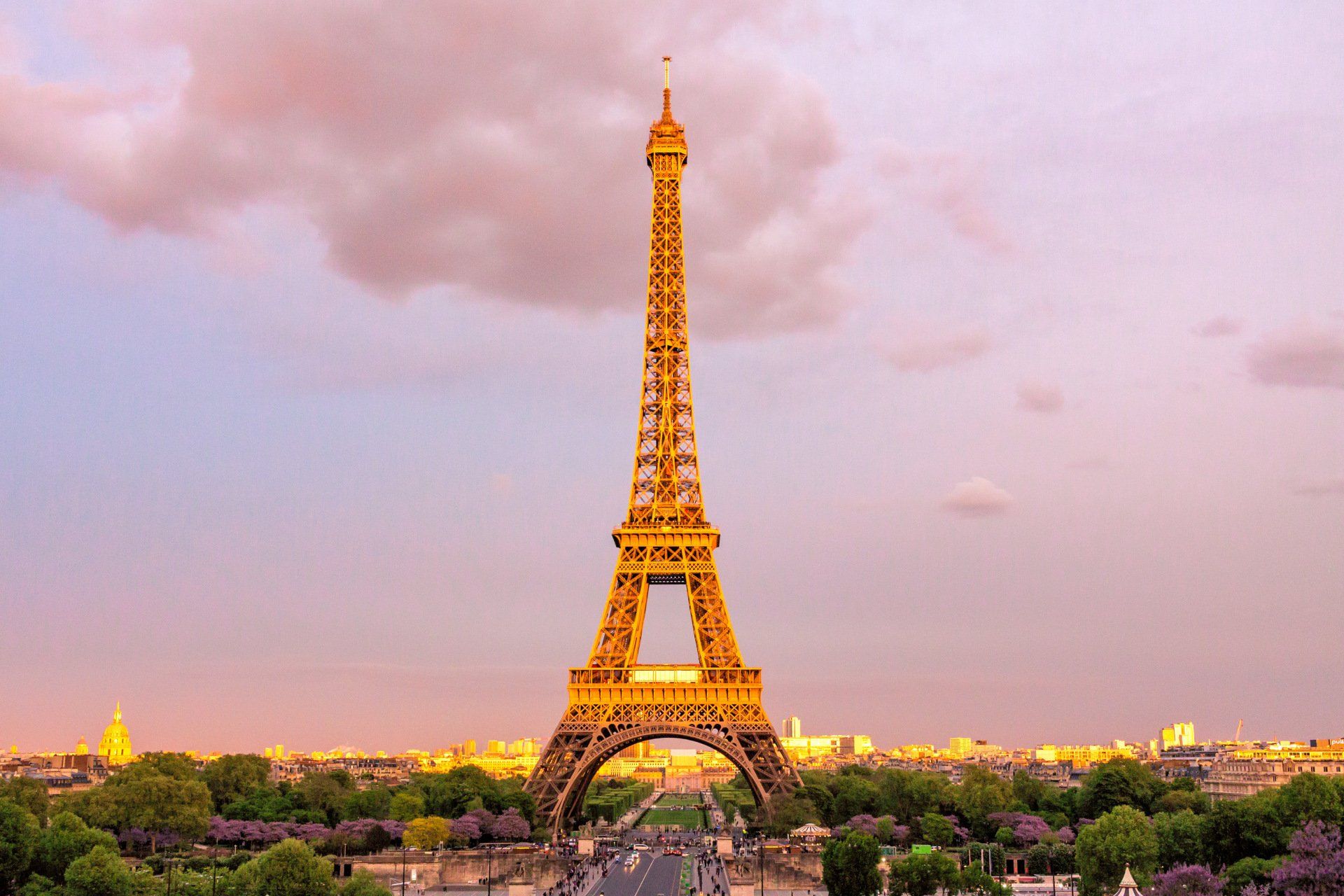 The eiffel tower is lit up at sunset in paris.