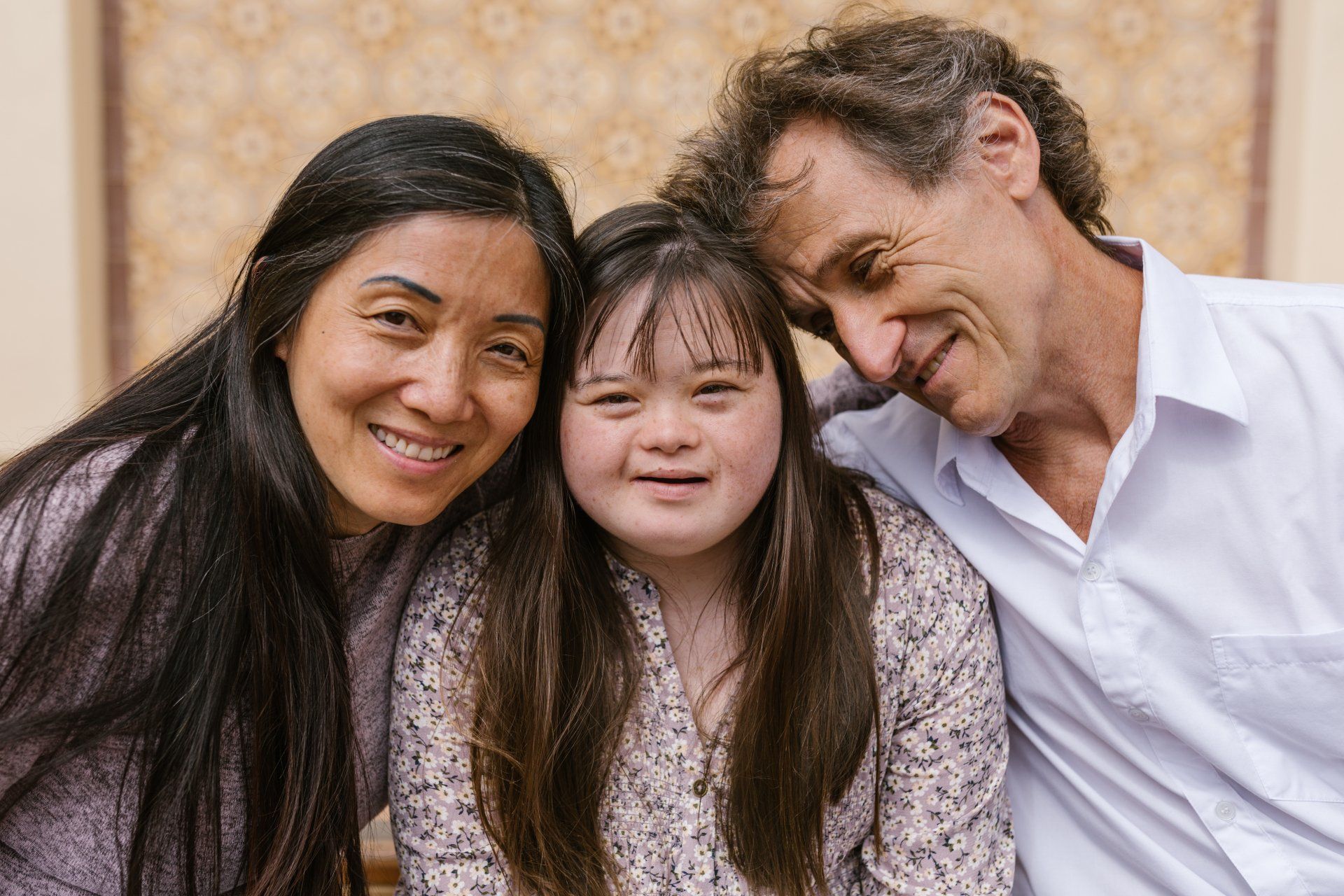 A man and a woman are posing for a picture with a girl with down syndrome.