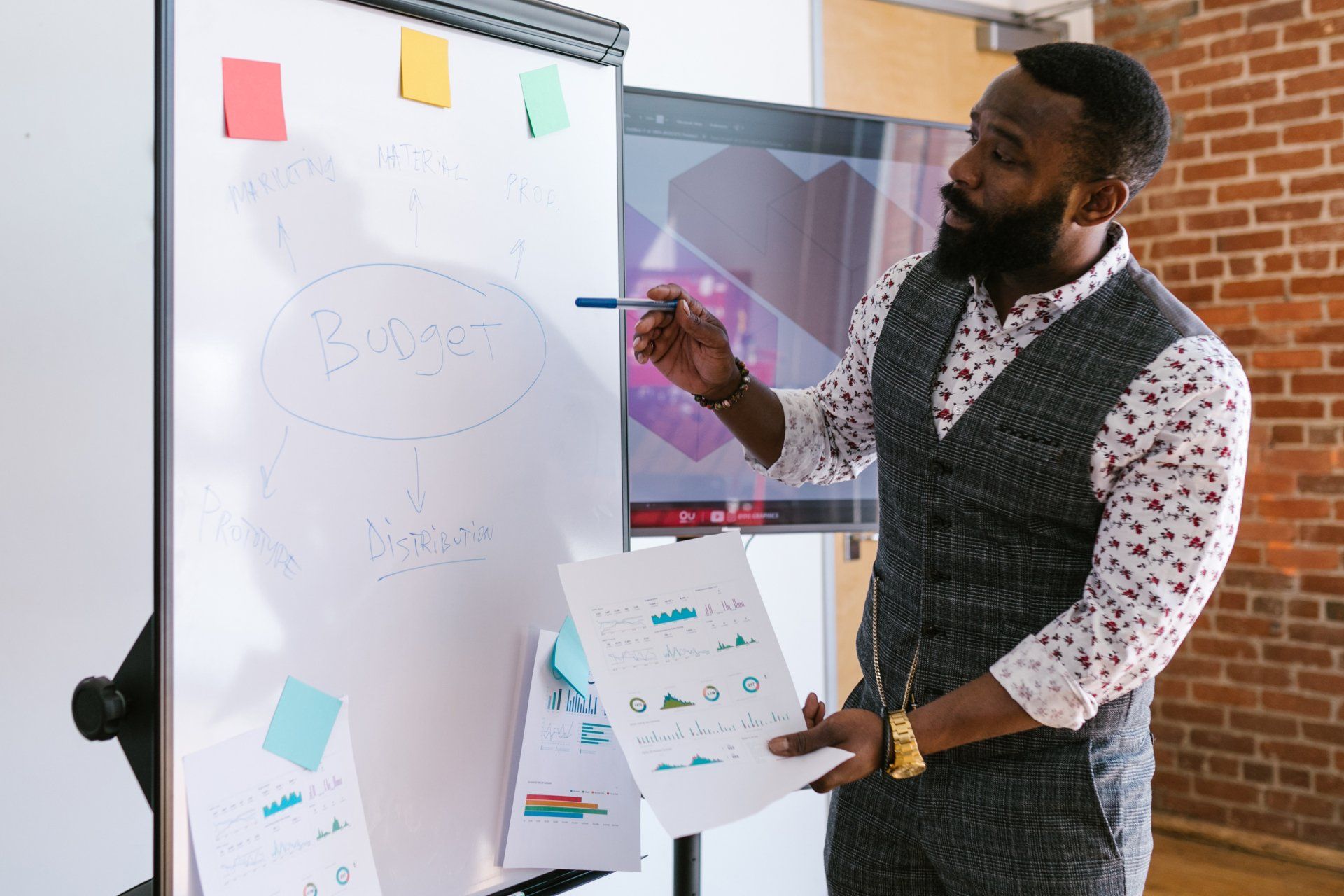 A man is giving a presentation in front of a whiteboard.