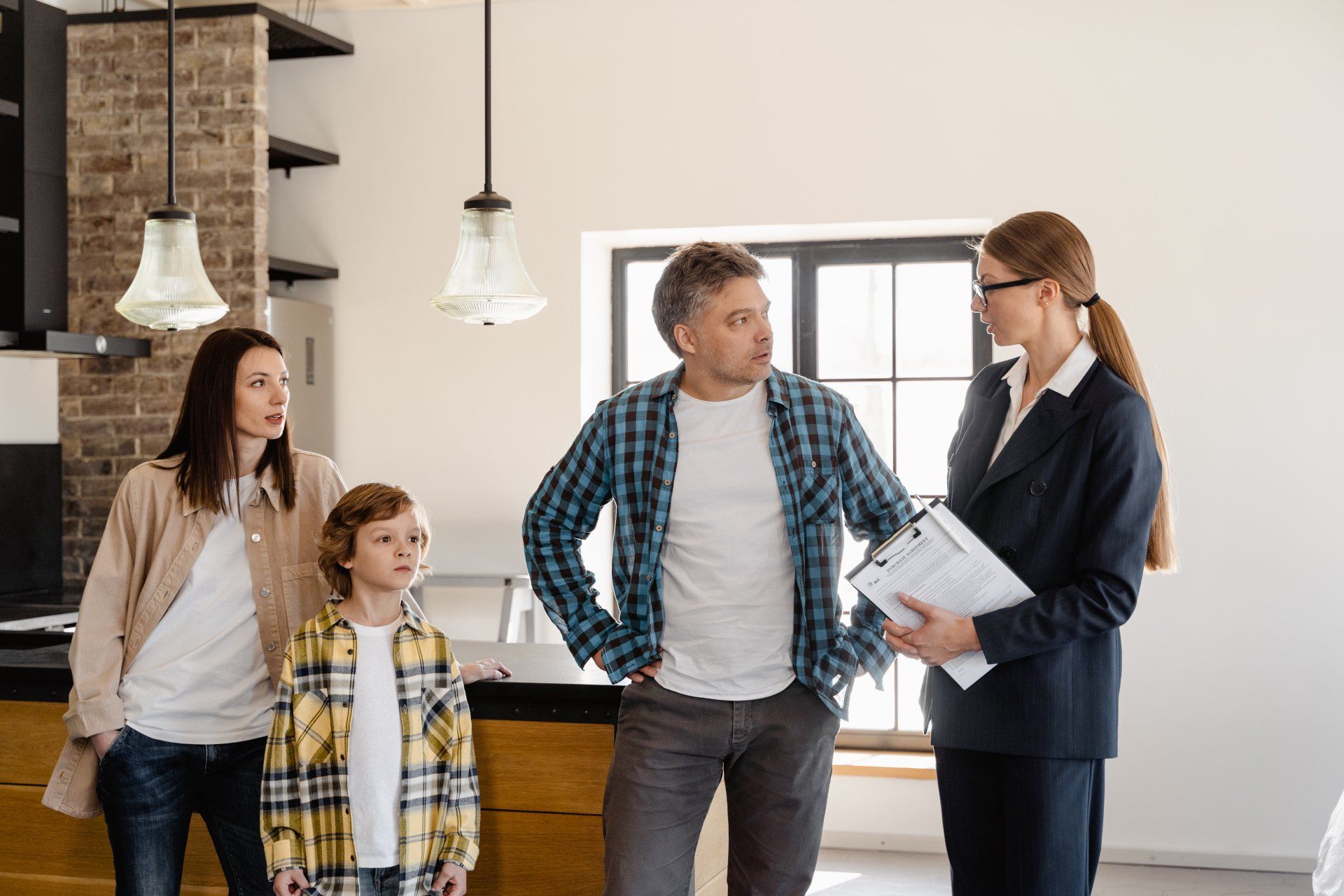 Family and realtor inside a home, discussing paperwork.