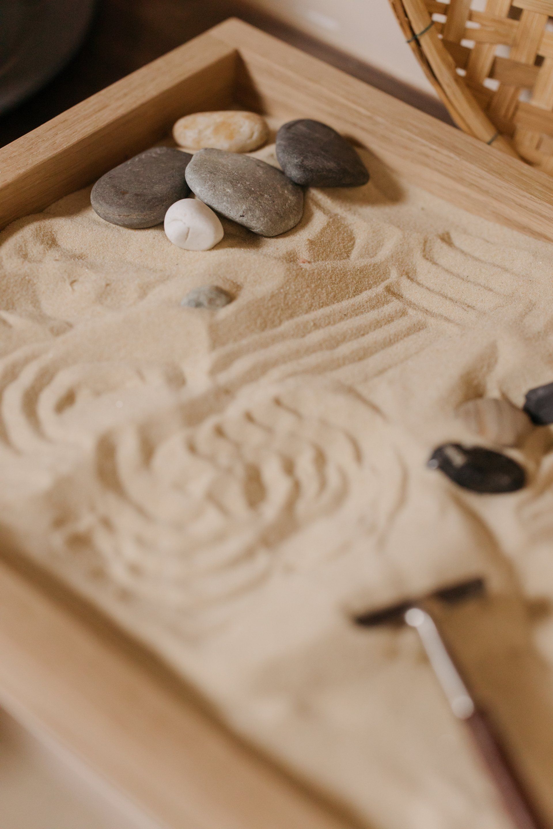 Zen-Sandgarten mit geglättetem Sand, Steinen und einem Rasiermesser.