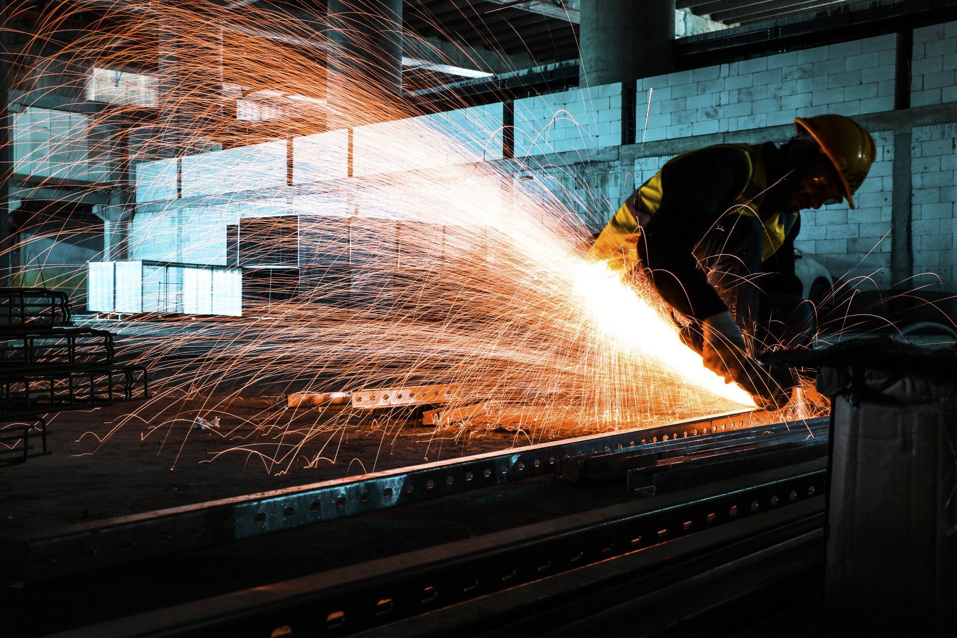 A Man is Cutting a Piece of Metal With a Grinder in a Factory — NQBC Pty Ltd in Bowen, QLD