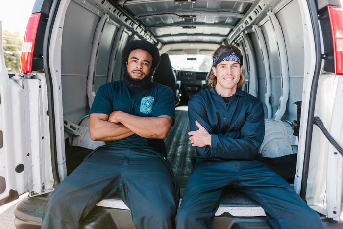 two movers sit on the tailgate of a moving van