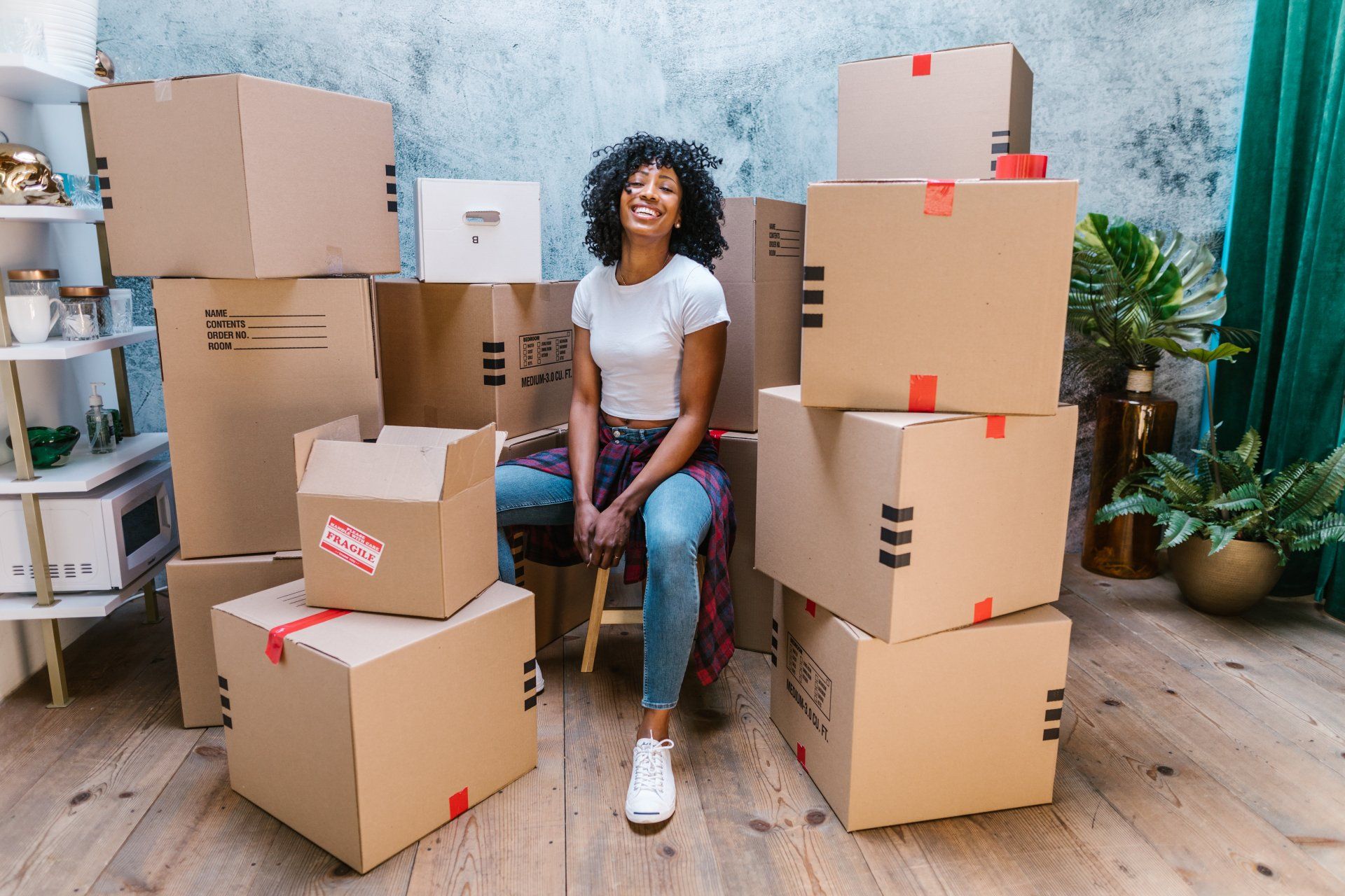A woman is sitting in front of a pile of cardboard boxes.