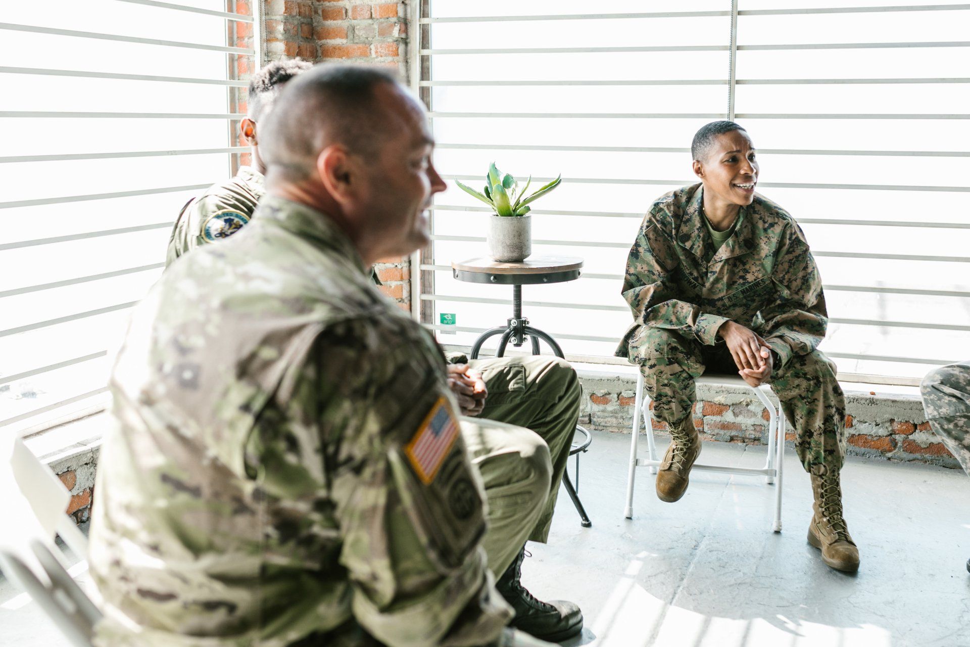 A group of soldiers are sitting in chairs talking to each other.