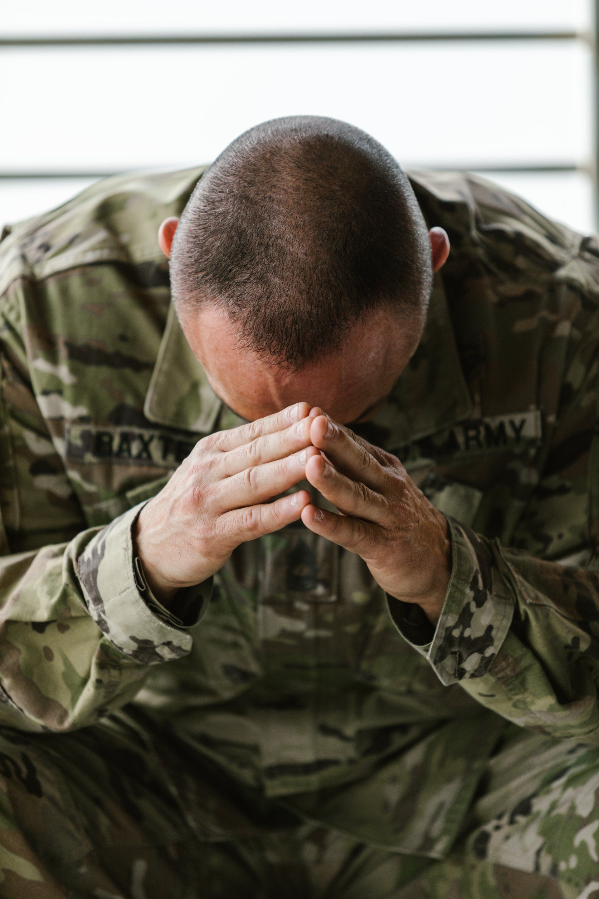 a soldier is kneeling down with his head in his hands .