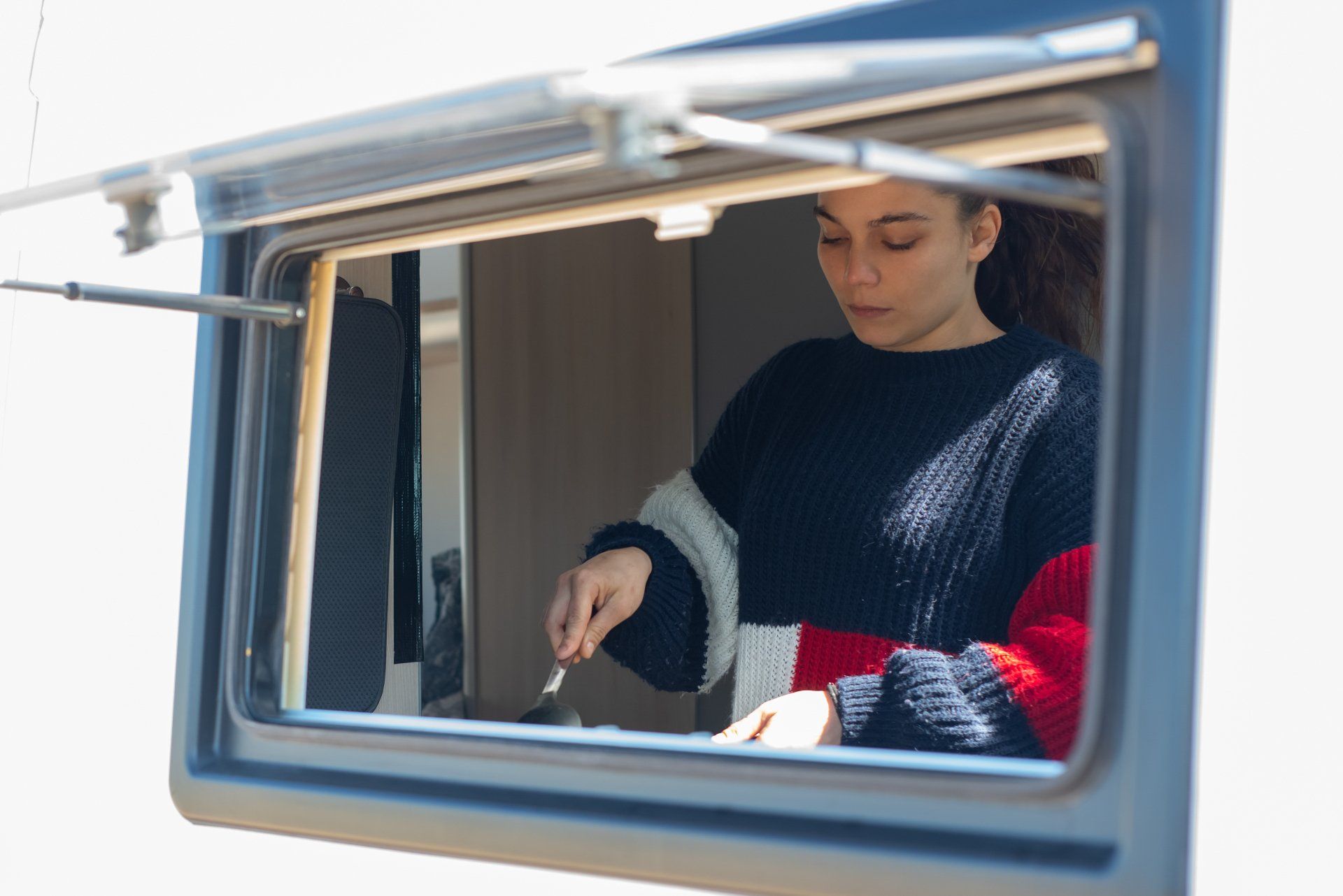 Vrouw kijkt uit het raam tijdens camperavontuur.
