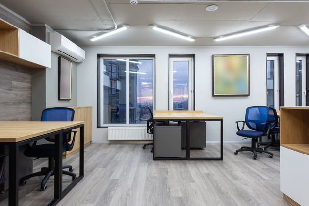 A modern office with a lot of windows and tables and chairs.