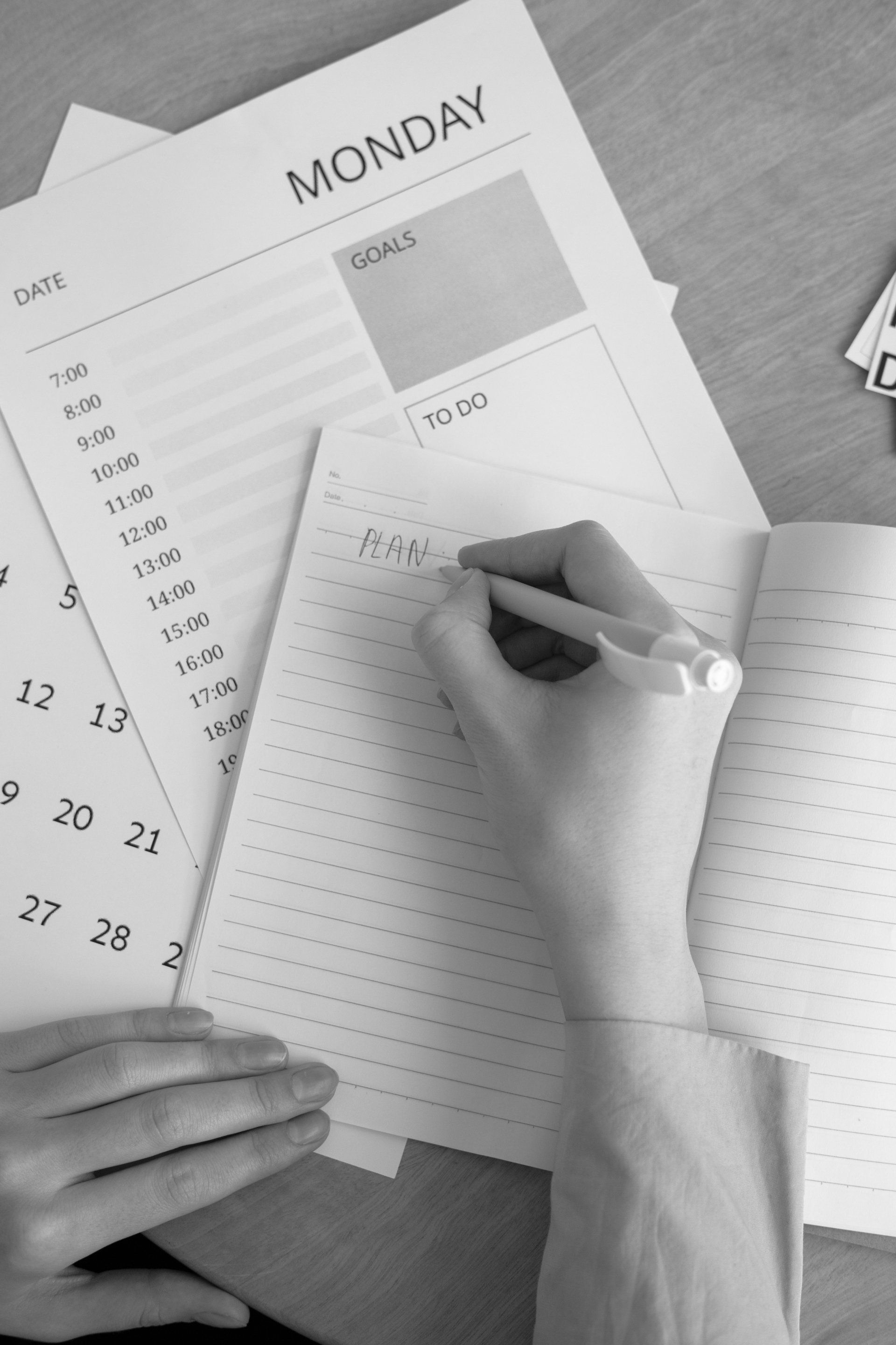 Hand writing on a weekly planner beside a calendar