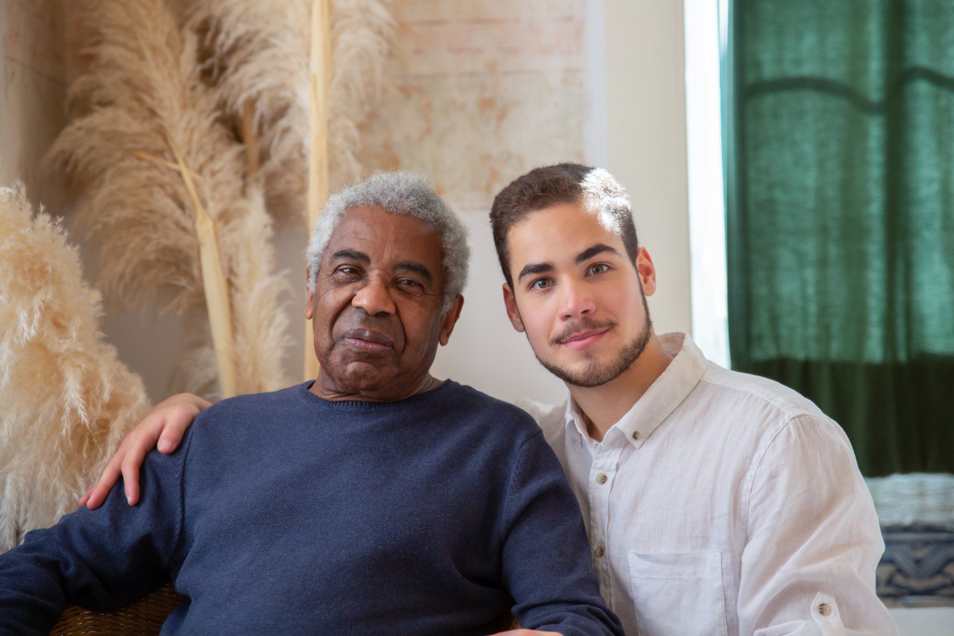 A young man is sitting next to an older man on a couch.