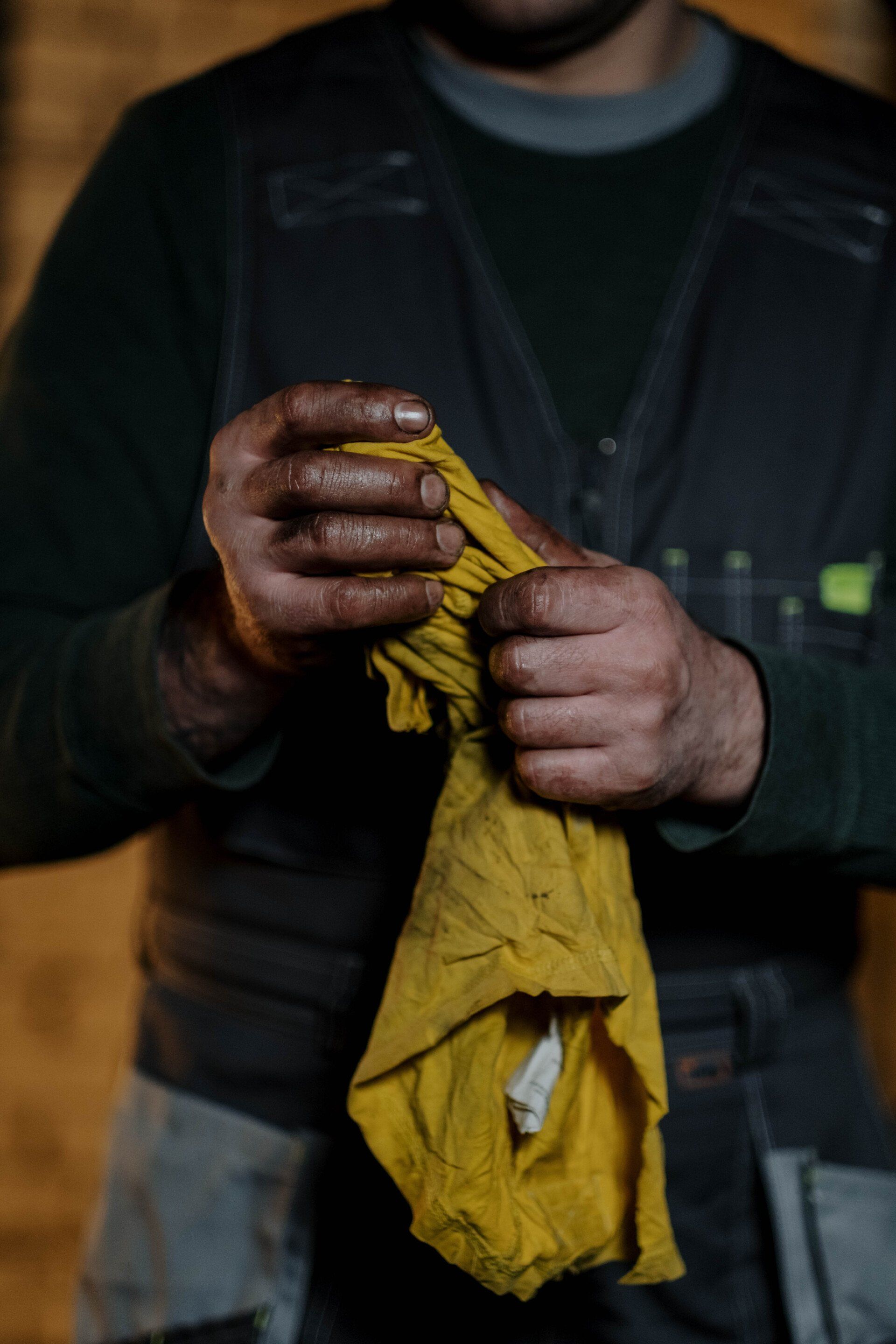 man wiping dirty hands on rag