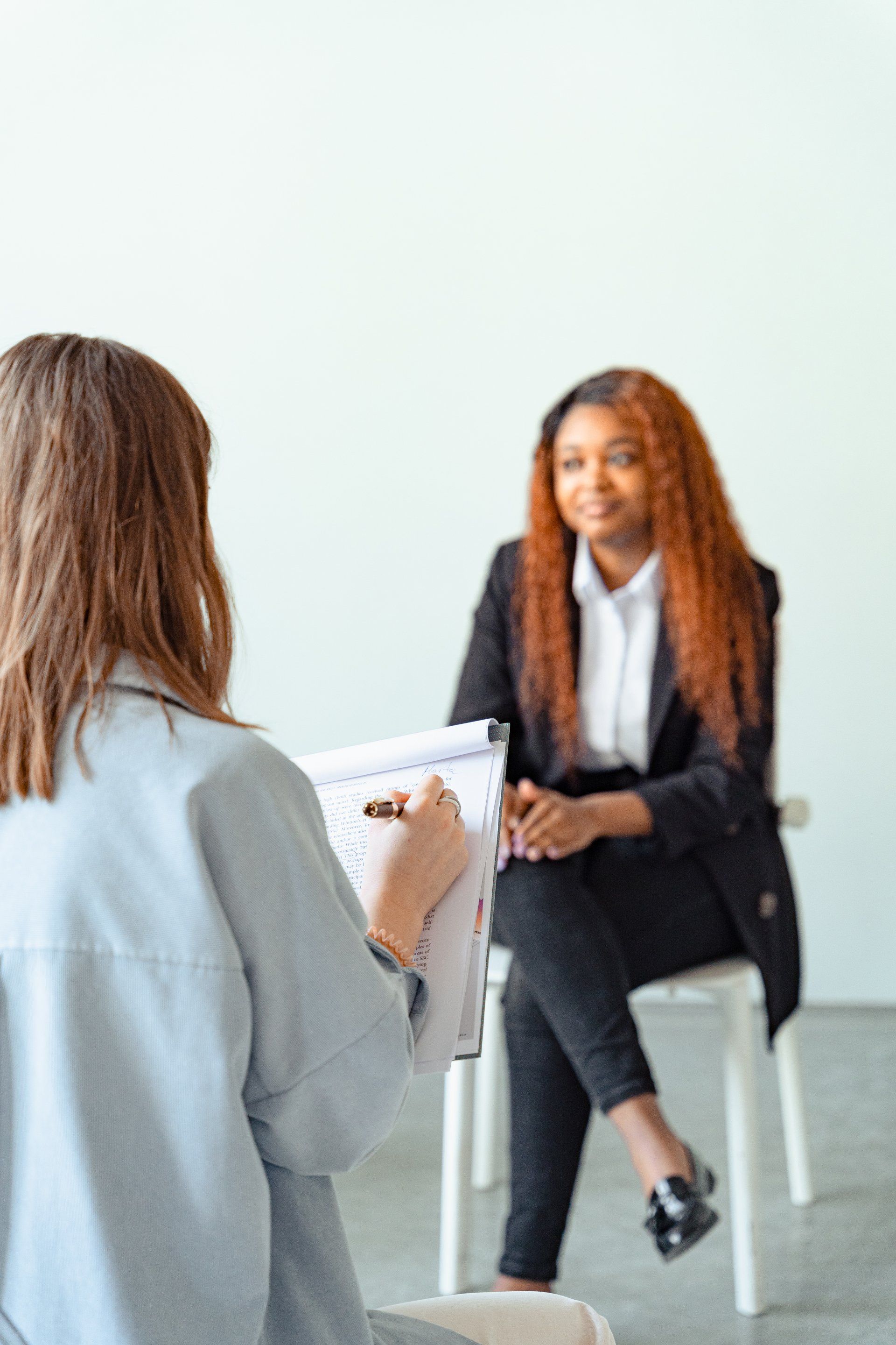 A woman is sitting in a chair talking to another woman.