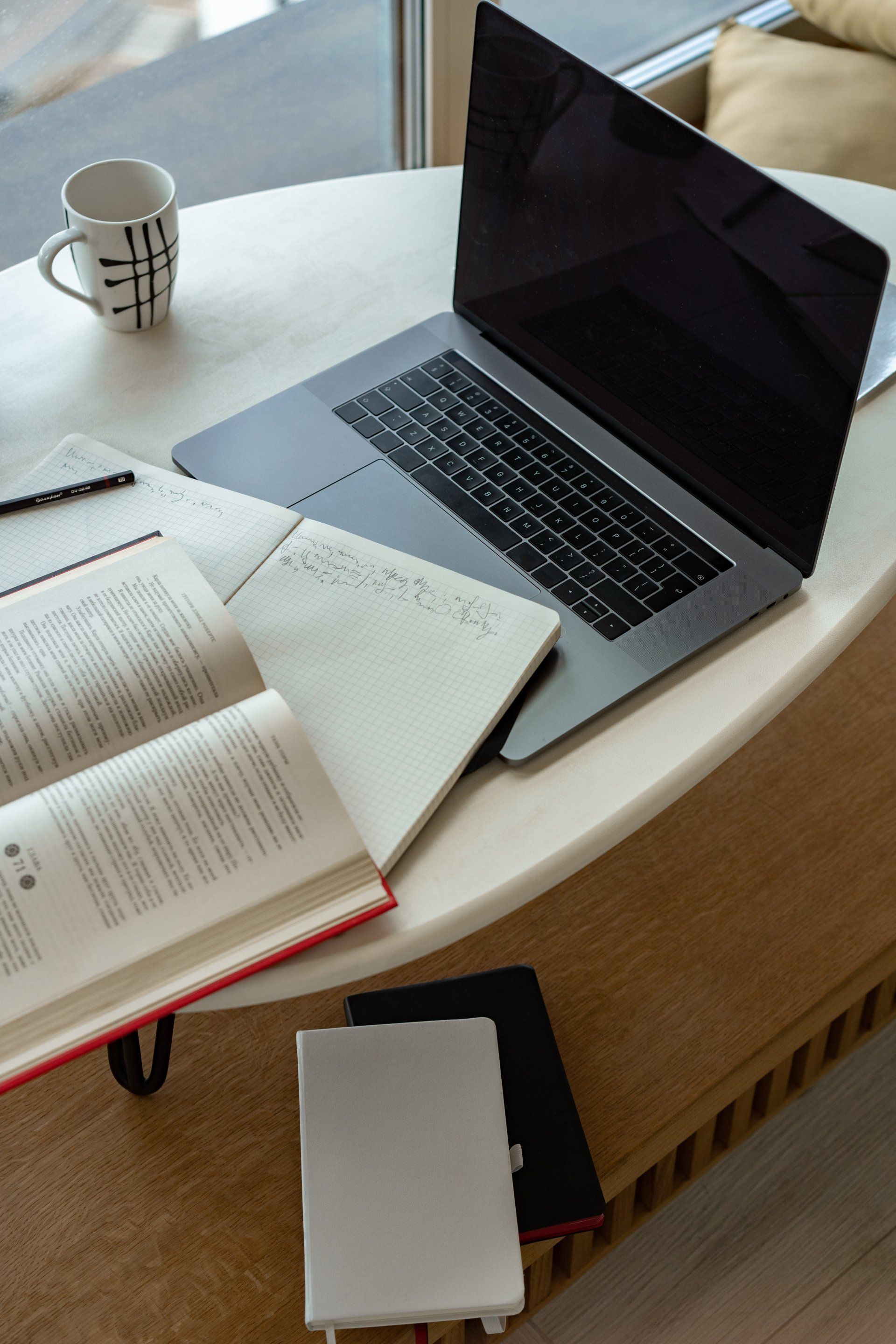 A laptop computer is open on a table with books and a cup of coffee.