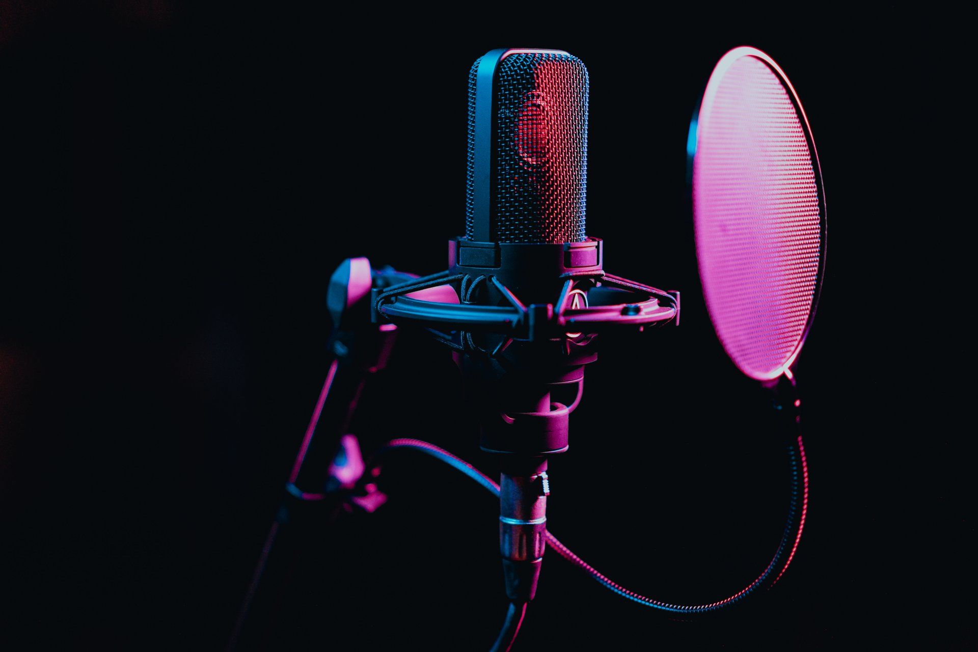 A close up of a microphone with a pink and blue light behind it.