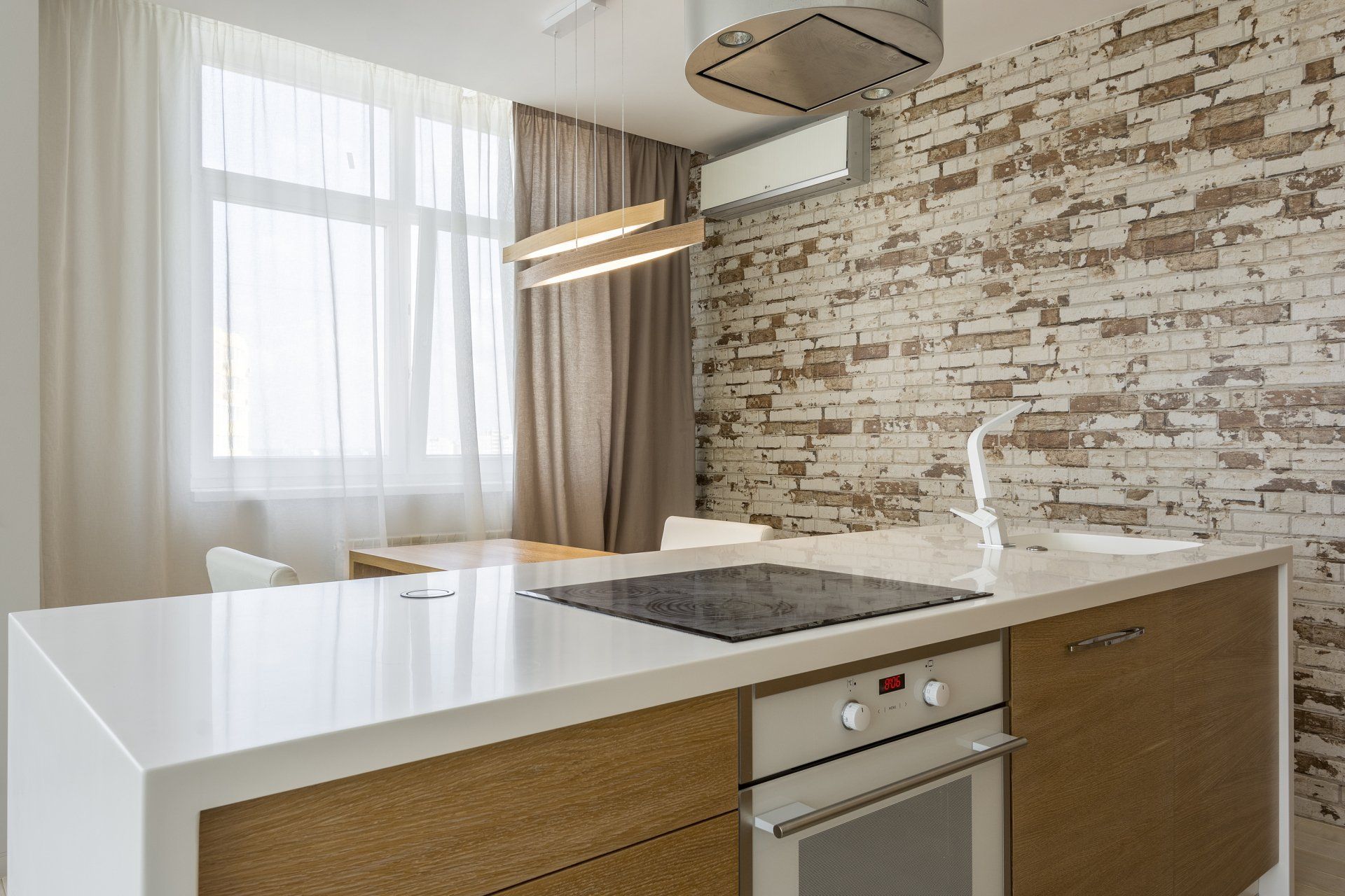 A kitchen with a stove top oven and a brick wall.