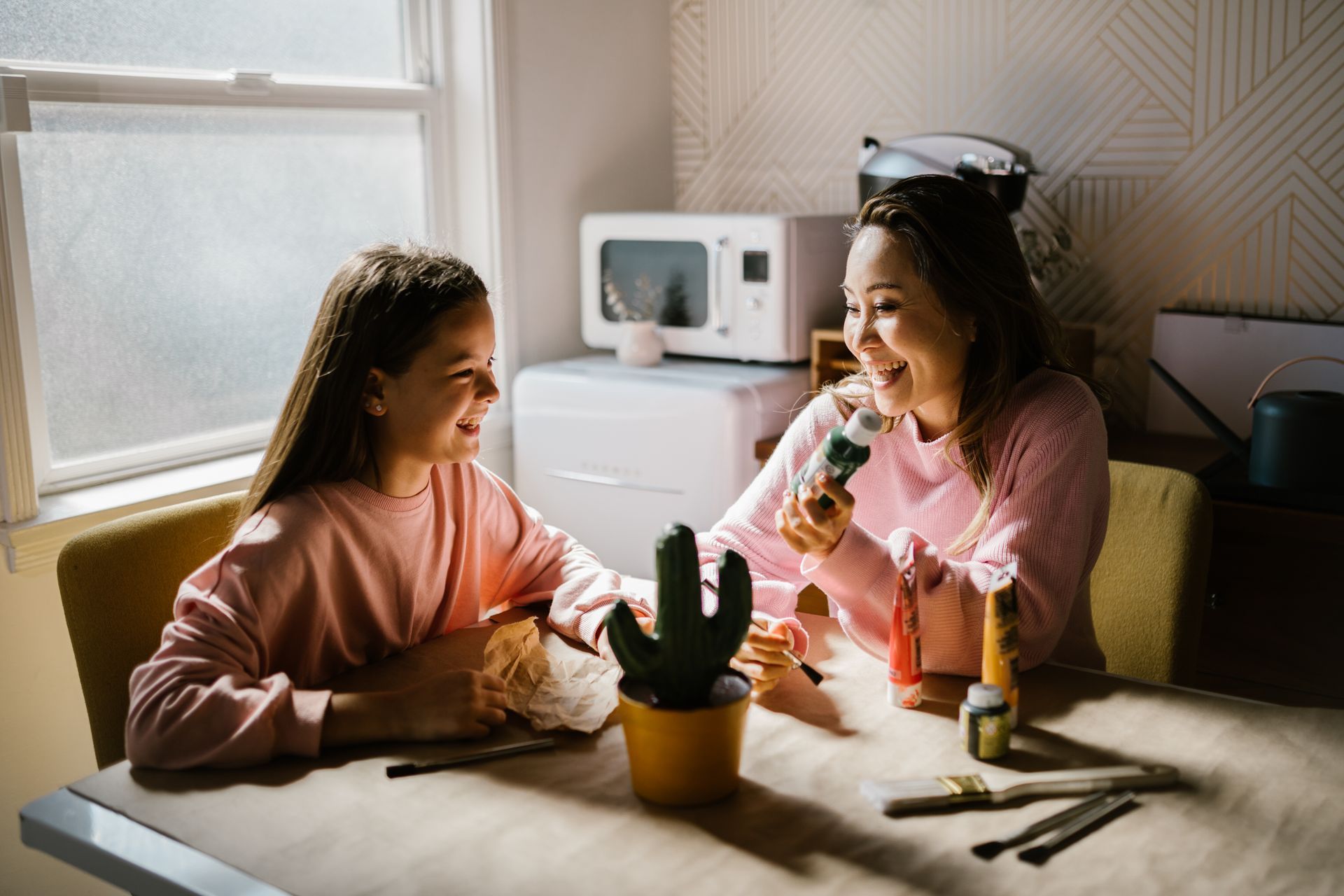 a mother and daughter are sitting at a table eating ice cream .