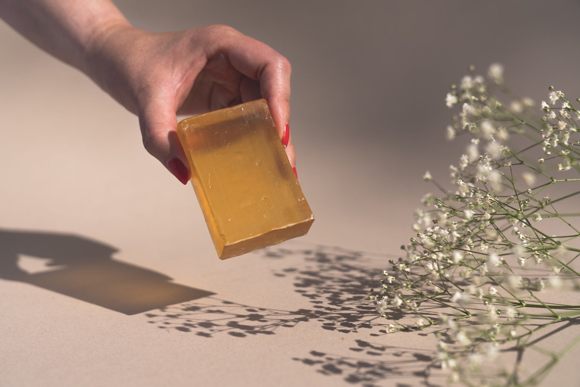 A person is holding a piece of soap next to flowers.