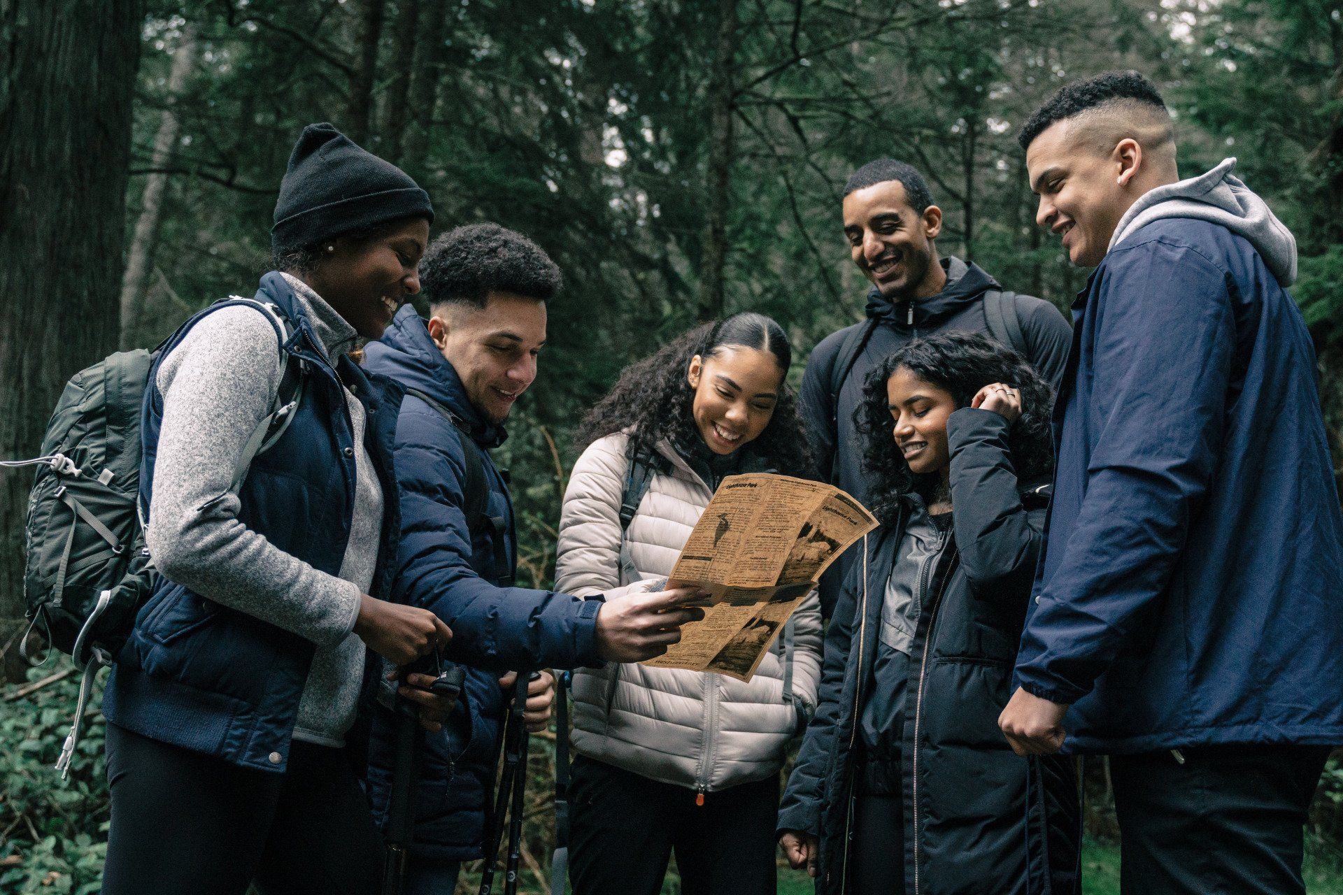 A group of people are looking at a map in the woods.