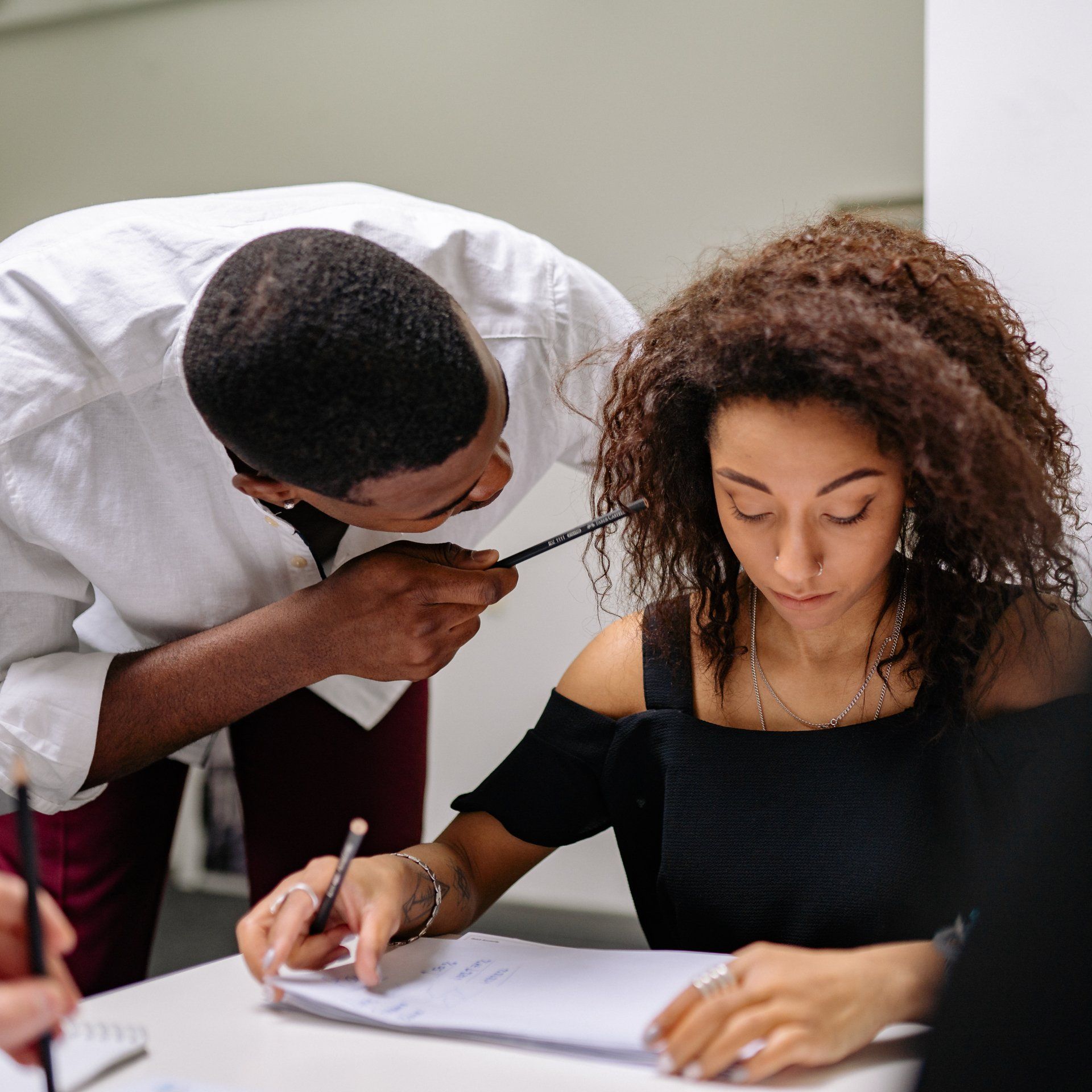 Man pointing pen at woman coworker
