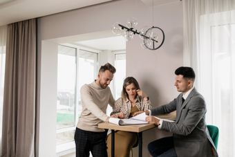 A man and a woman are sitting at a table with a man in a suit.