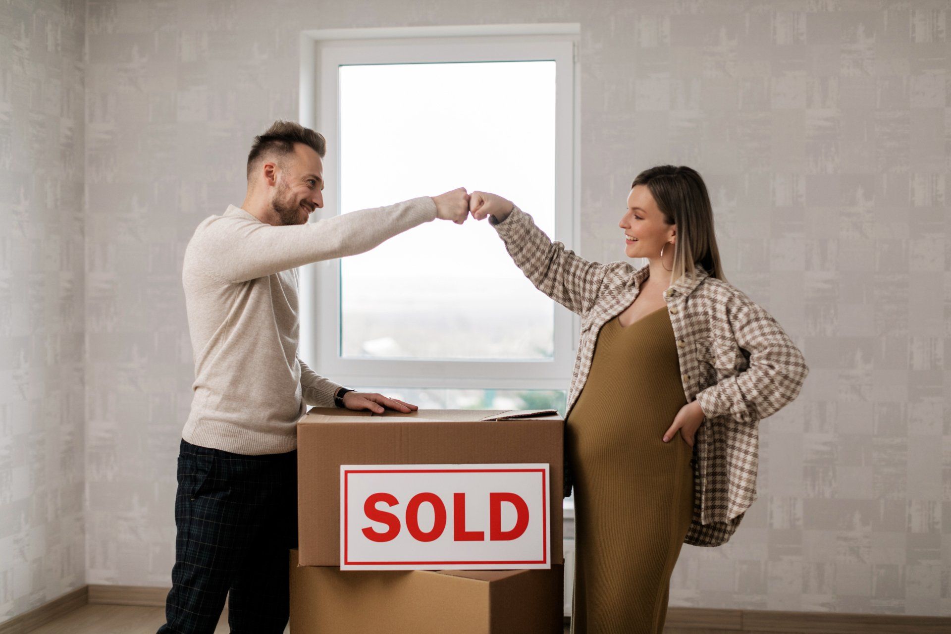 A man handing a box of auction-sold items to a pregnant woman who bought the items at a high selling price
