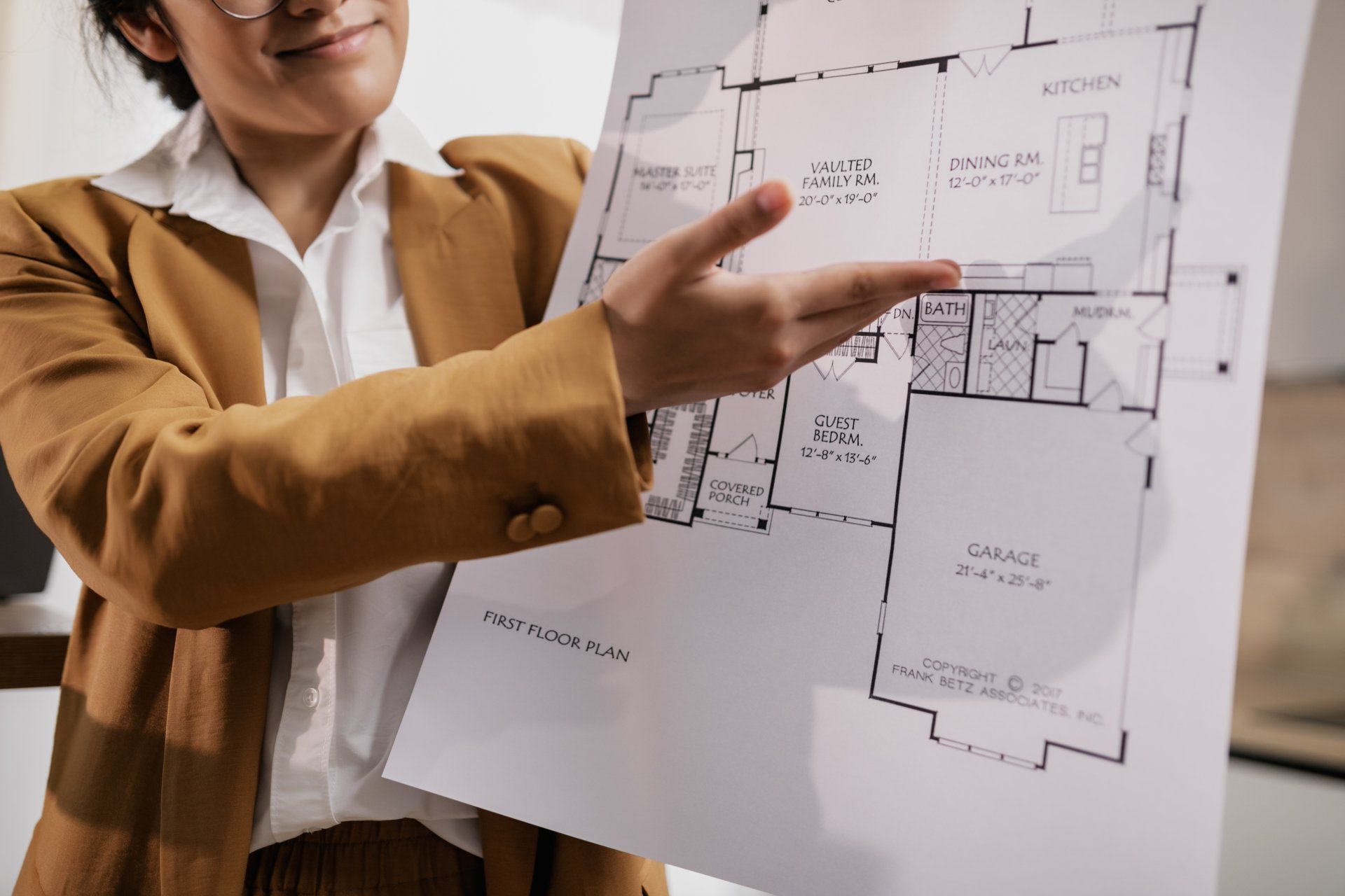 A woman is pointing at a floor plan of a house.