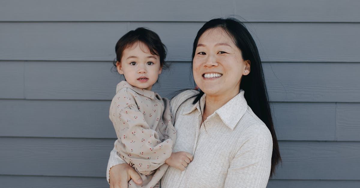 a woman is holding a baby in her arms in front of a gray wall .