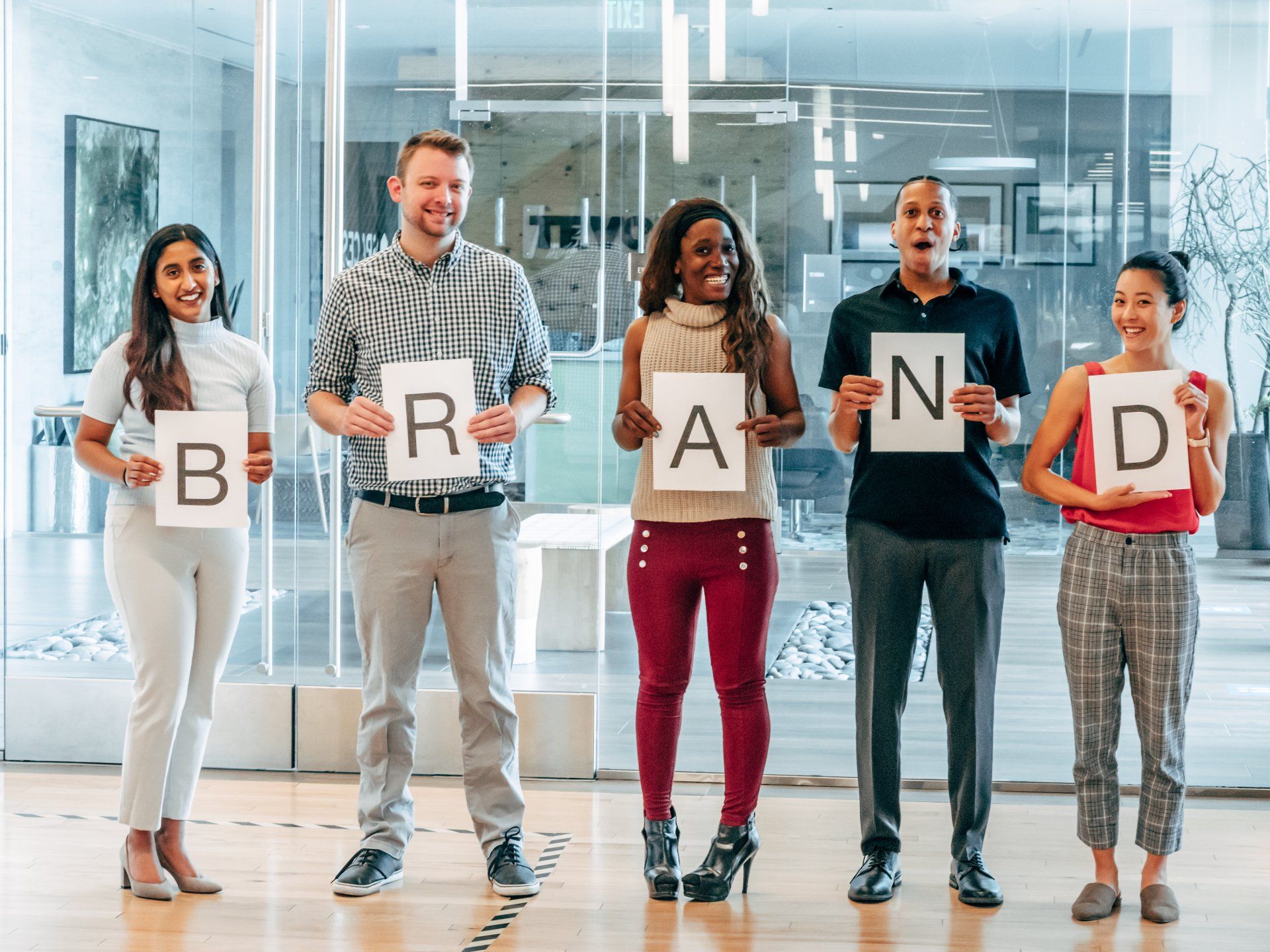 Your culture is your employment brand. Build it right. Five employees standing holding letters that collectively spell Brand.