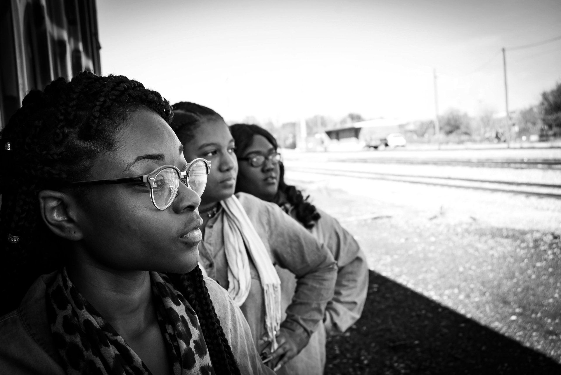 Three women wearing glasses are standing next to each other in a black and white photo.