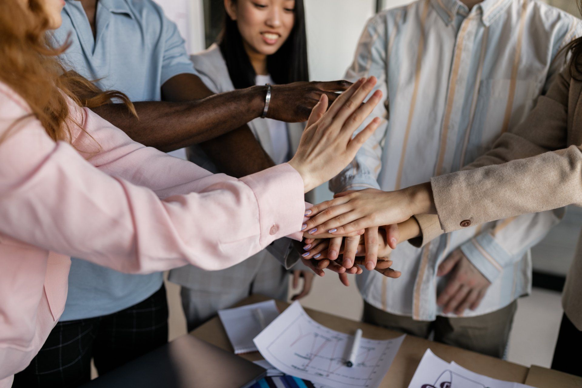 A group of people are putting their hands together in a huddle.