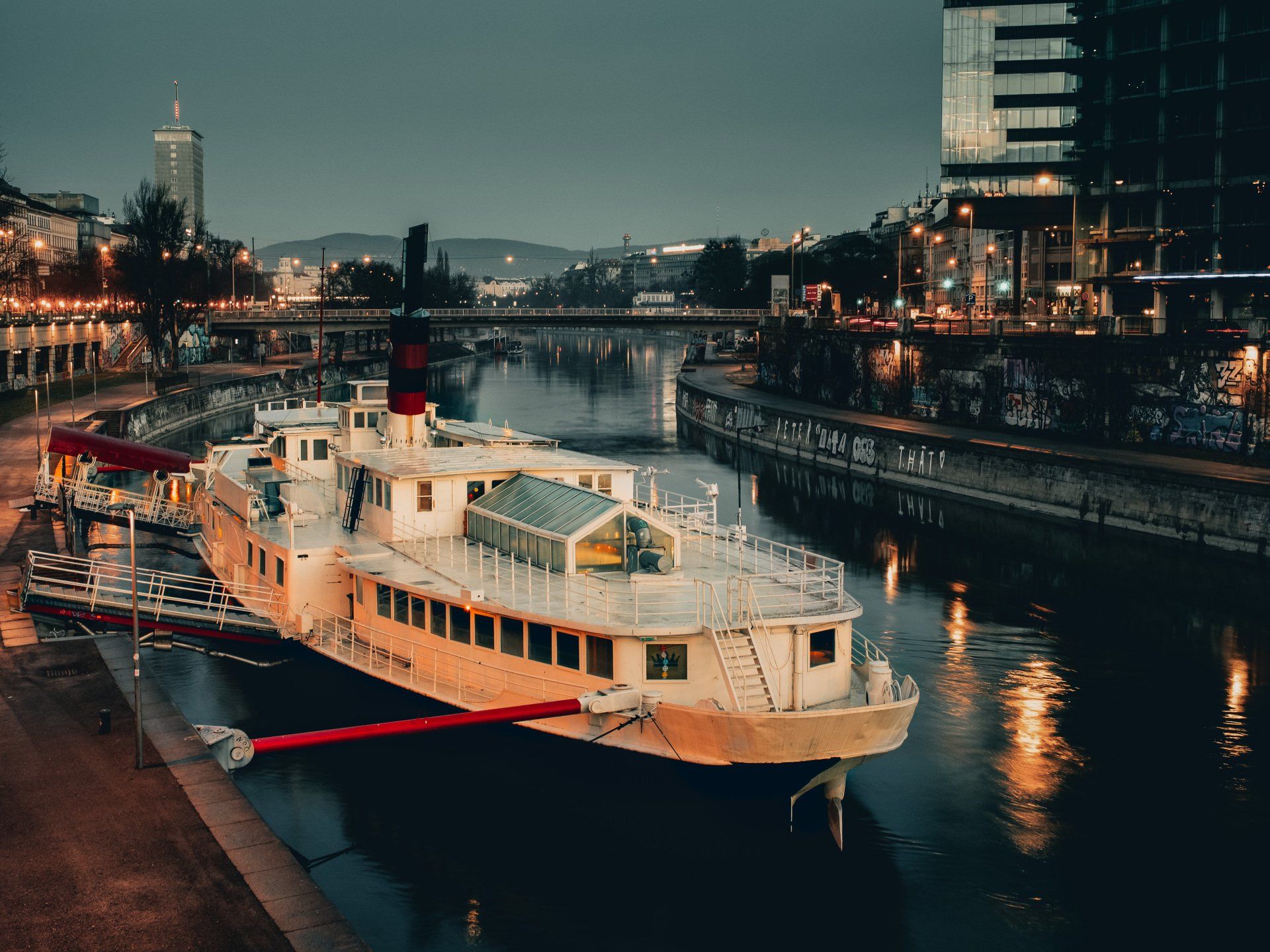 Nachtaufnahme der Donau, im Fokus eine beleuchtete Feere. 